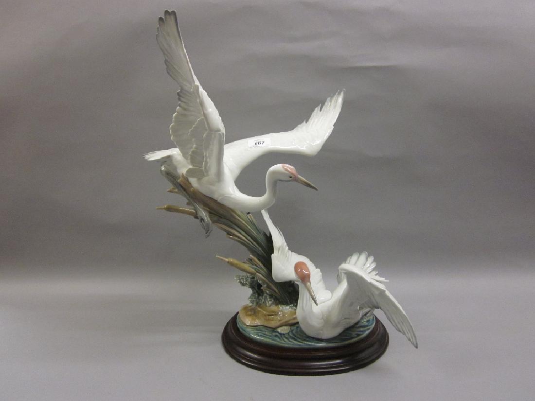 Large Lladro group of two cranes with outstretched: Large Lladro group of two cranes with outstretched wings beside bulrushes, 21ins high, including the oval wooden plinth base, with original box