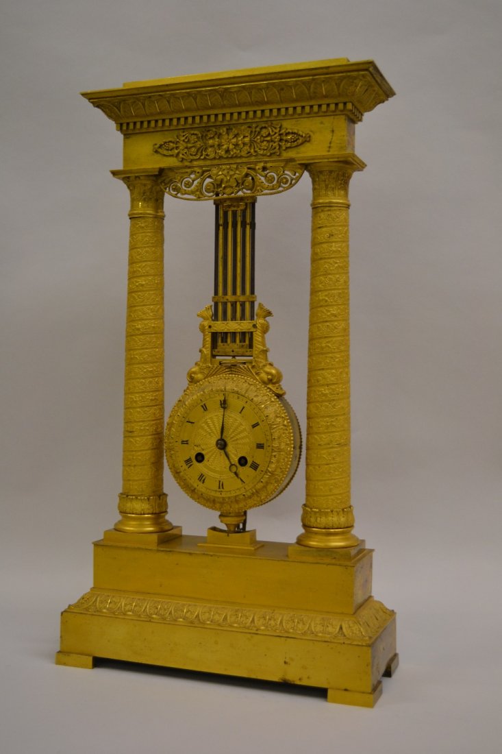 19th Century French Empire ormolu portico clock of neo: 19th Century French Empire ormolu portico clock of neo classical form with a gilded dial having Roman numerals, the two train movement striking on a bell