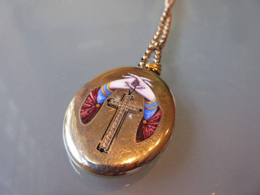 Victorian yellow metal locket decorated in coloured: Victorian yellow metal locket decorated in coloured enamels with clasped hands above a cross on an unmarked yellow metal chain