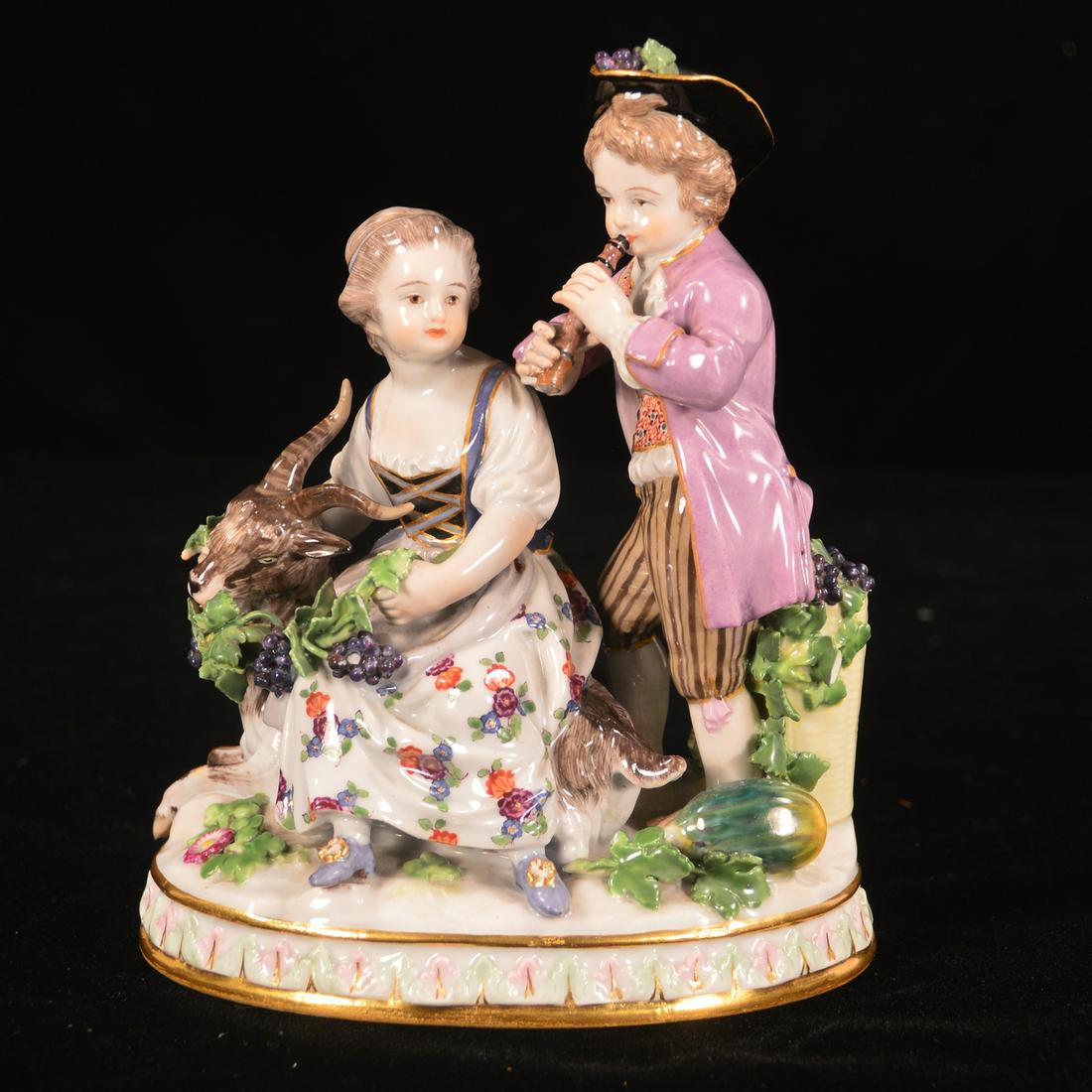 Meissen figural group: Meissen porcelain figural group of a young man and woman, he is playing a flute while she is seated on a goat, 5" wide, 6.5" high