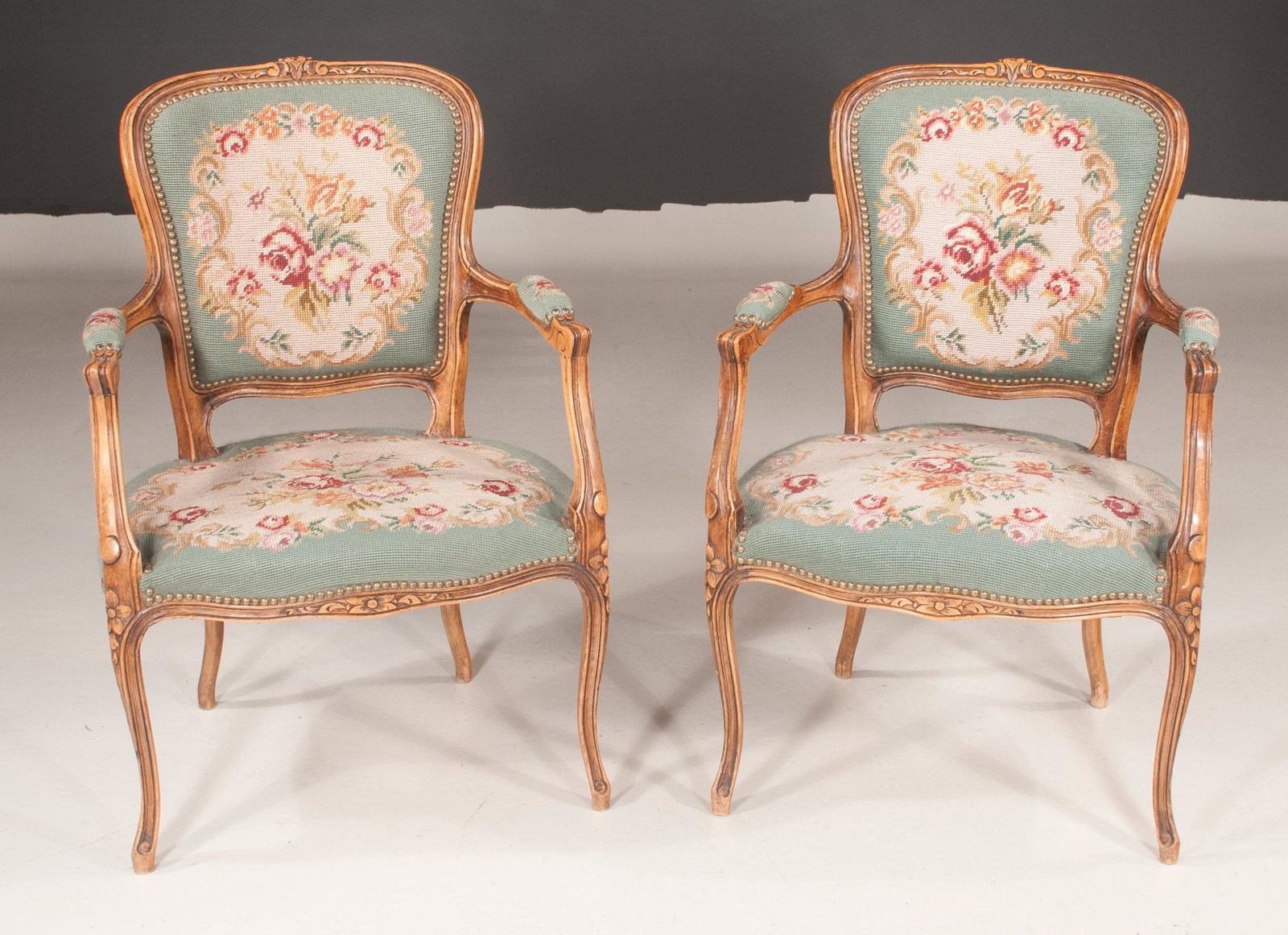 Pair of Country French walnut upholstered armchairs: Pair of Country French walnut upholstered armchairs with floral carved dome back crest, scroll carved arms, floral carved apron, on cabriole legs with floral carved knees and having needlepoint uphols