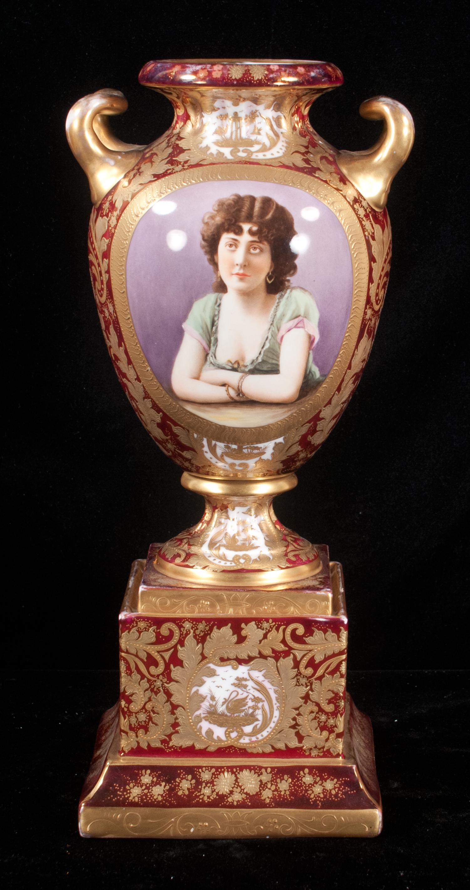 Royal Vienna double handle vase: Royal Vienna double handle vase with cranberry background and gilt leaf decoration having a panel portrait of a young lady leaning on a table set on a matching plinth, 16" high
