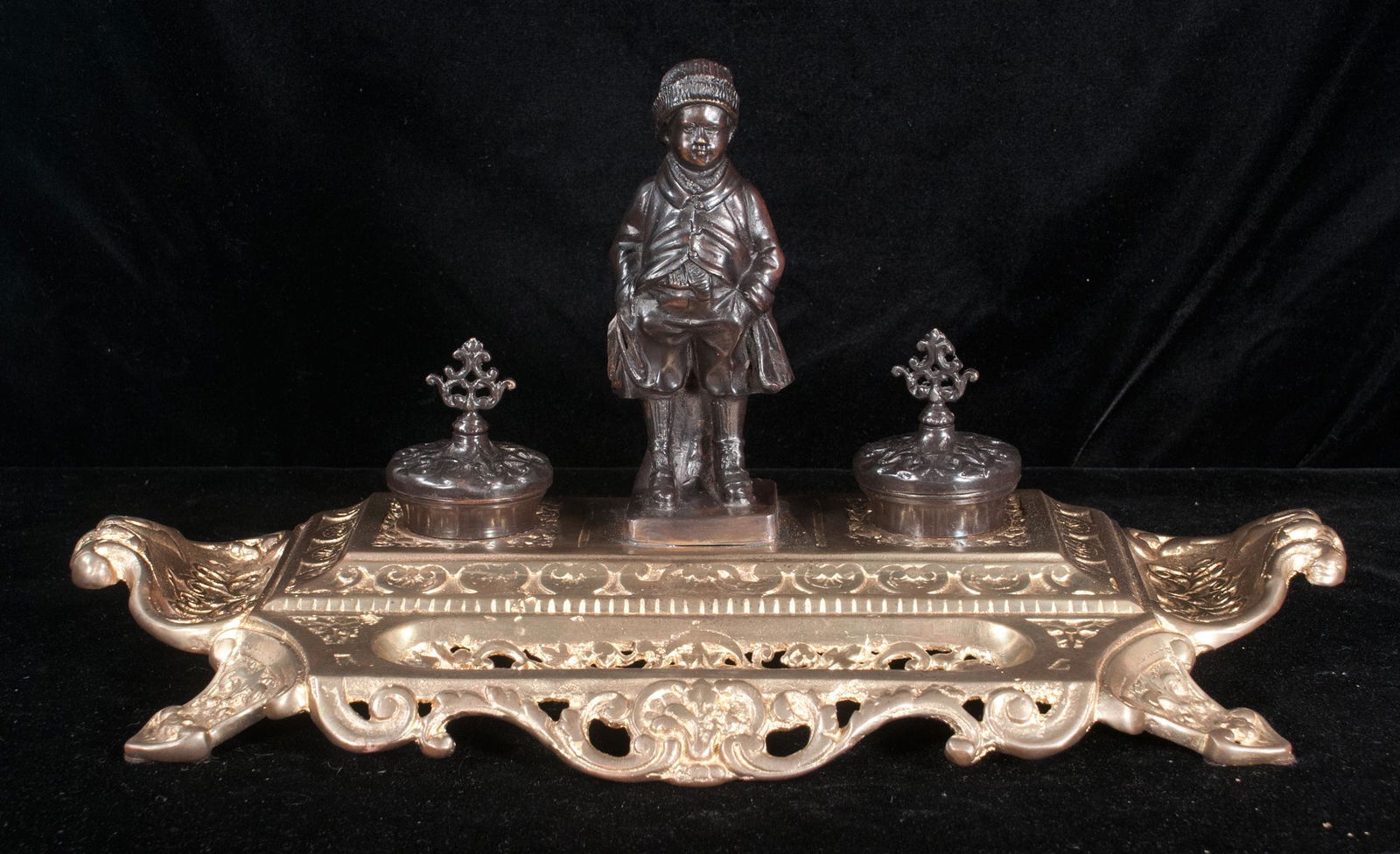 Bronze desk set: Bronze desk set with figure of a young boy in the middle, two covered inkwells on a gilt bronze filigree base with double handles, 19.5" wide, 7.5" deep, 9.5" high