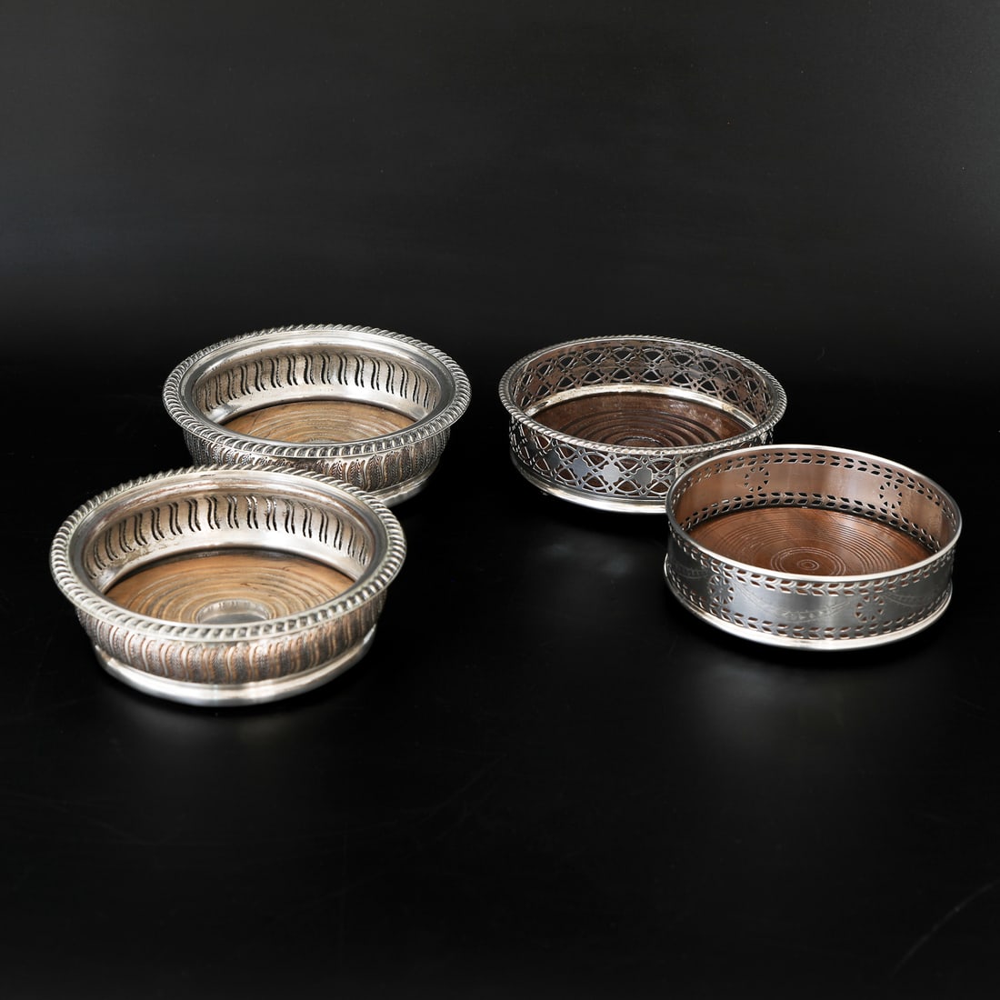 Grouping of Silver Plated and Wood Wine Coasters, Four Total: Grouping of Silver Plated and Wood Wine Coasters, Four Total, Includes a Pair of Philip Ortele Silver Plated Wine Coasters Having Reeded Top Edge abd Pierced Leaf Design Bodies, 5.75" Diameter, 2" Hig