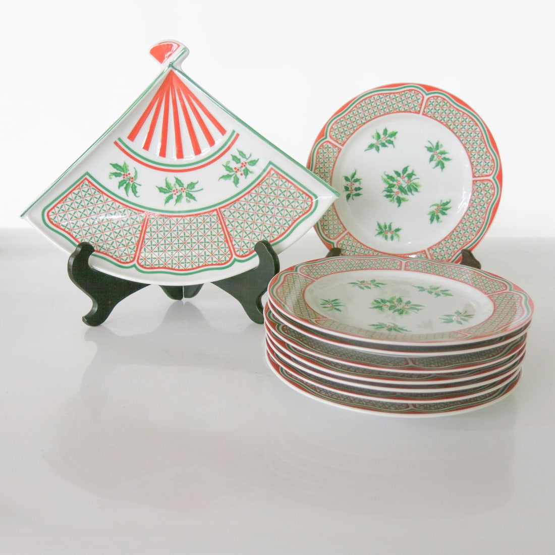 Group of Taste Seller by Sigma Noel Pattern Salad/ Dessert Plates and Fan Shaped Dish, Nine Total: Group of Taste Seller by Sigma Noel Pattern Salad/ Dessert Plates and Fan Shaped Dish, Nine Total Pieces, Having Holly Sprigs in Center Surrounded by Diamond Pattern and Holly Leaves Having Red Border