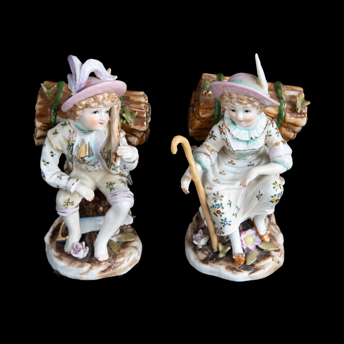 Vintage Porcelain Figures, Pair: Vintage Porcelain Figures, Pair, Female Sitting on Tree Form, Holding Shepard's Crook, Bundle of Logs on Her Back, Wearing Hat with Feather, Along with Male Figure Sitting on Tree Form, Having Bundle