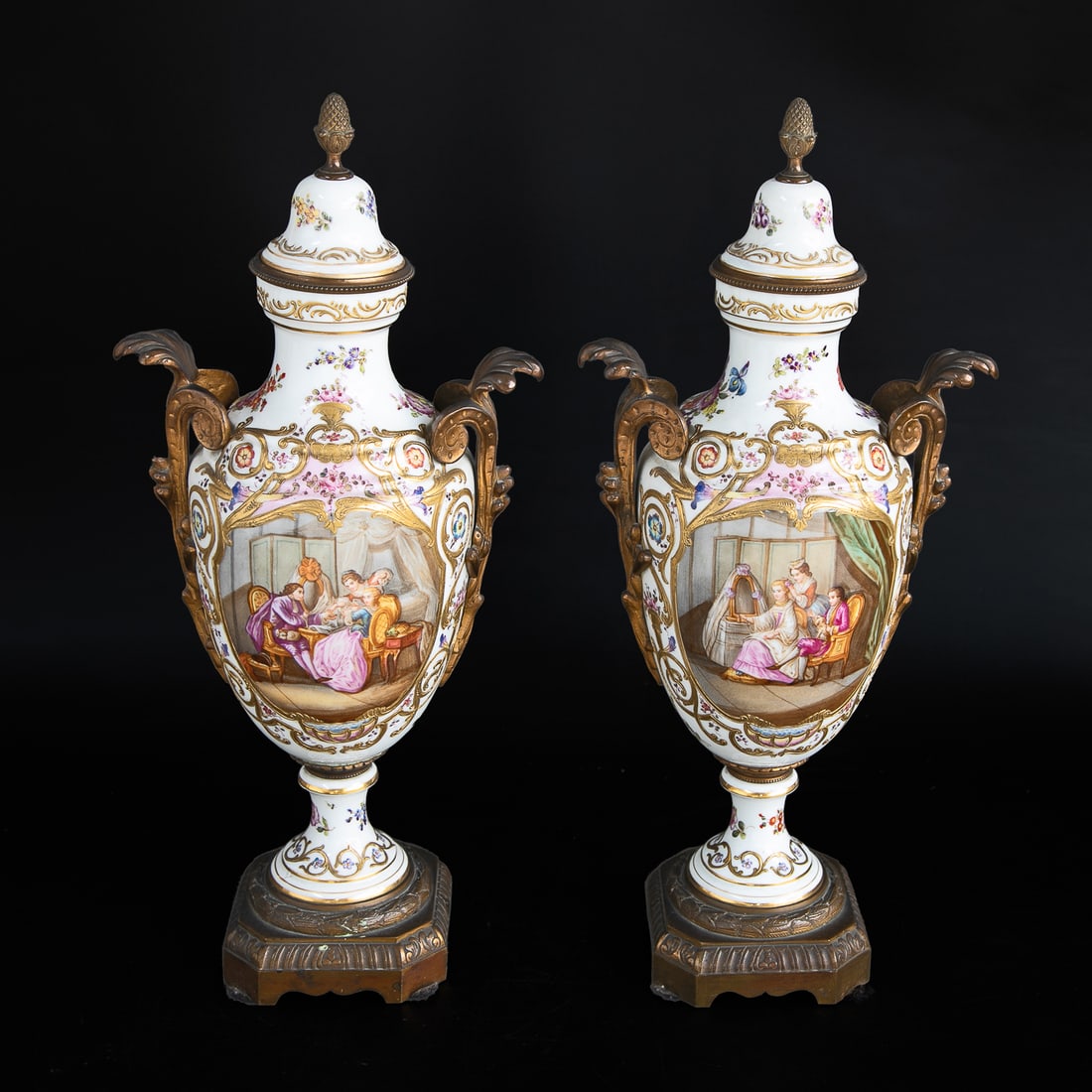 Late 19th C. French Sevres Porcelain Urns, Pair: Late 19th C. French Sevres Porcelain Urns, Pair, Having White Ground, Bronze Acorn Finial Atop Lid, Multi Color Floral Decorations, Back Panels Feature Landscape Scene, Front Panels Feature Parlor