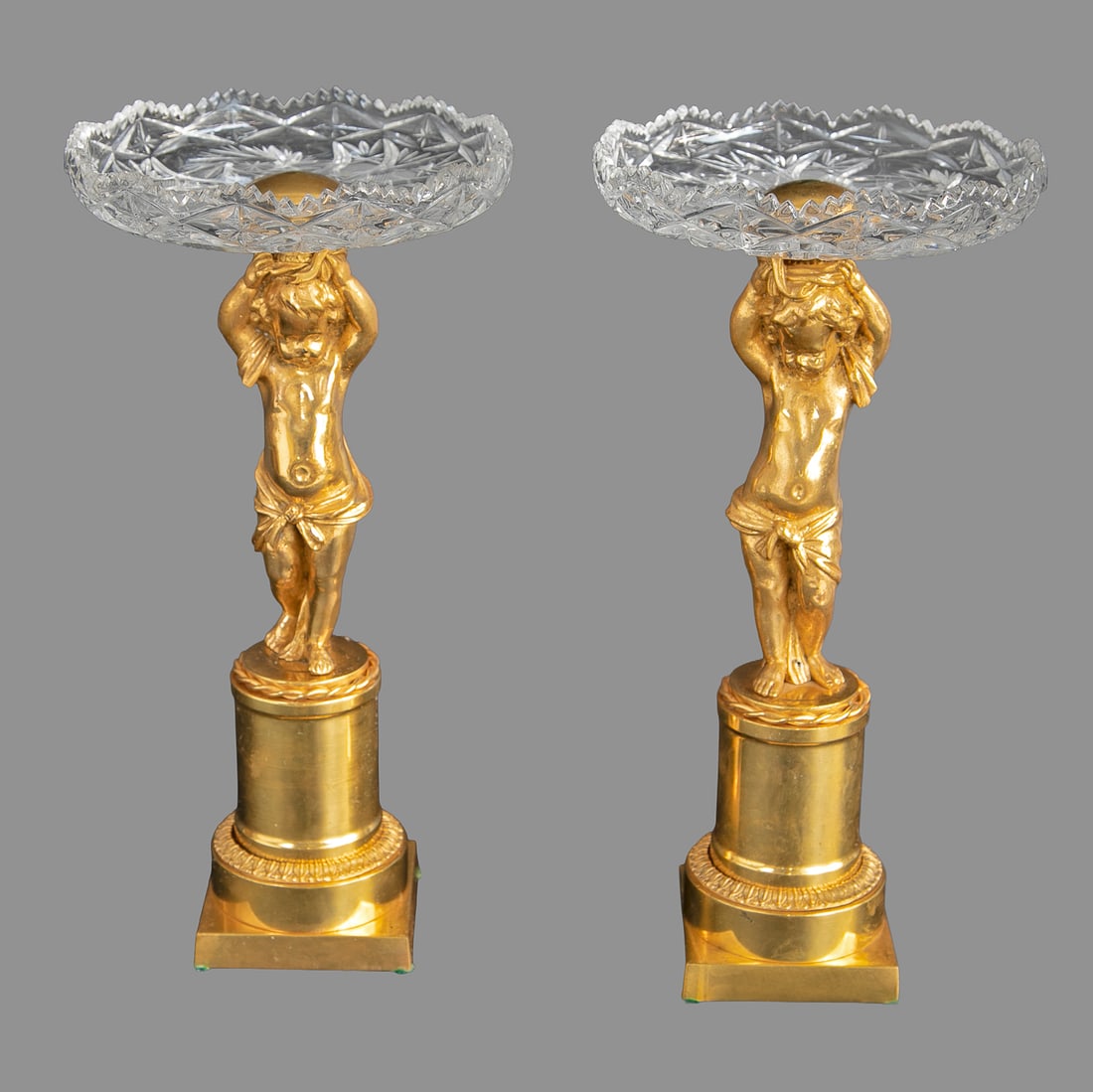 Vintage Gilt Bronze and Cut Glass Putti Compotes, Pair: Vintage Gilt Bronze and Cut Glass Putti Compotes, Pair, Having Putti Center Support Holding Cut Glass Top, Standing on Circular Plinth Style Base. 12" High, 6" Diameter