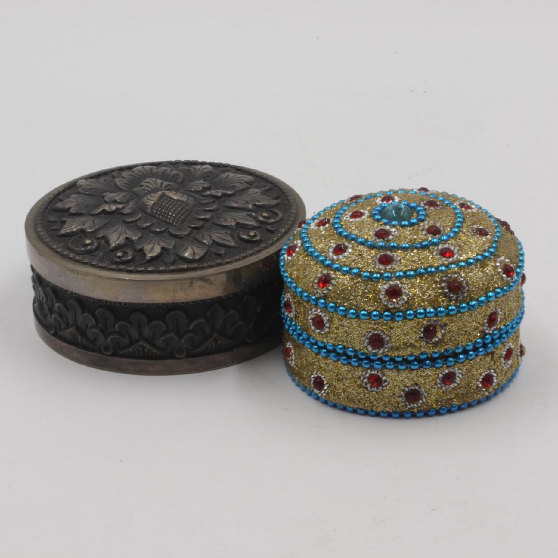 Two Decorative Boxes: Estimate: $5-$10 Description: Two small vanity boxes. One is decorated with good filigree design. The other is a repousee vine. Dimensions: large is 3"