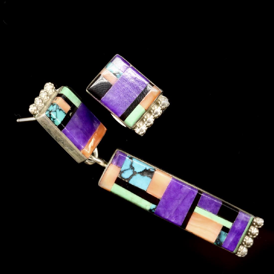 Turquoise, Onyx, Coral and Mounted in Sterling Silver: Estimate: $60-$75 Description: Turquoise, onyx, coral and purple sugilite mounted in sterling silver earrings. Asymmetrical designed earrings. One earring (larger): 2.5 inches long 11g The other (smal