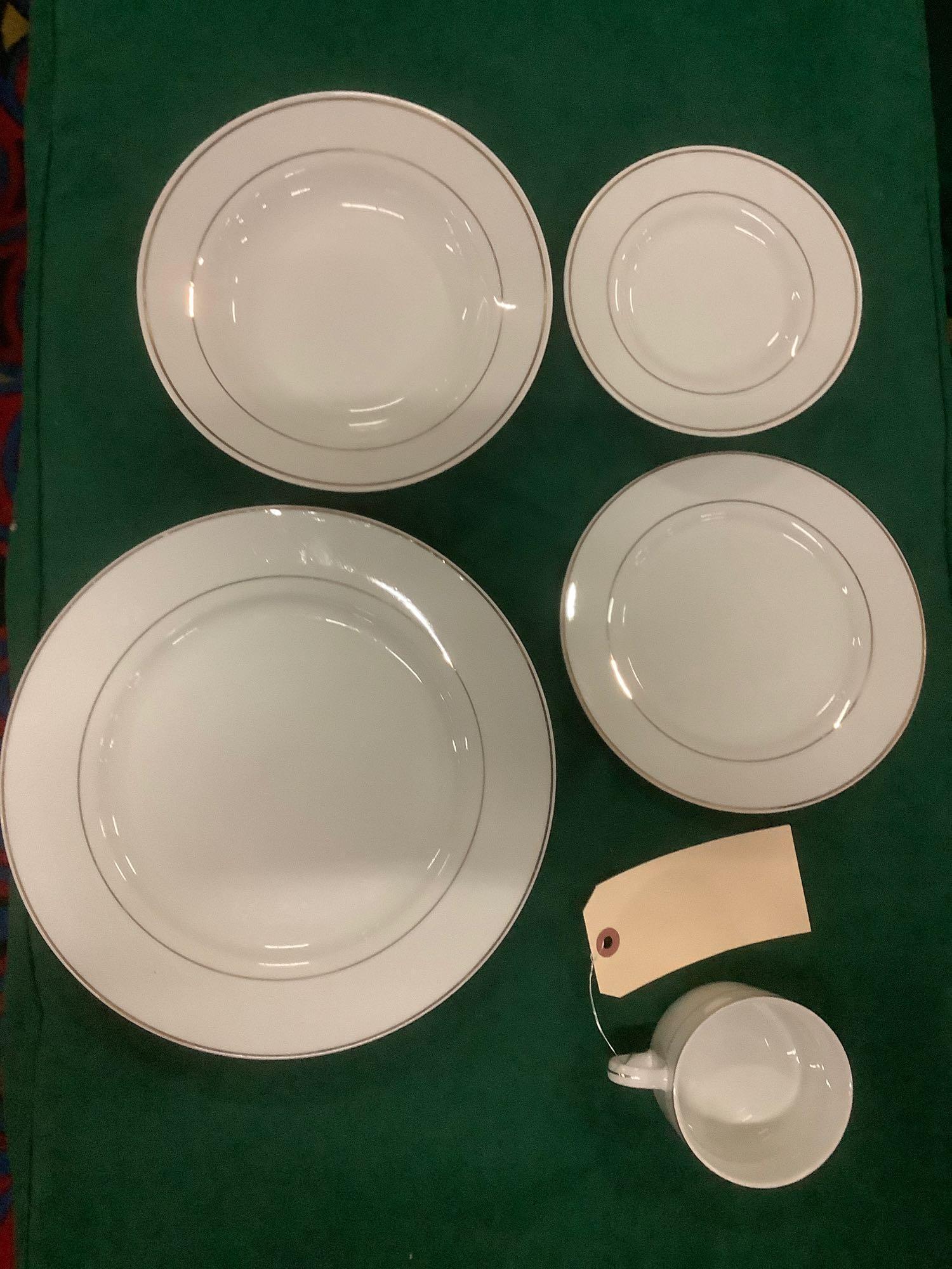Over 1800 pieces of Gibson Housewares china sets with 6: 6 wooden rolling carts filled with Institutional sized collection of Gibson Housewares China sets with green cloth dust covers. Lot includes approximately; 370 dinner plates, 392 salad plates, 381 des