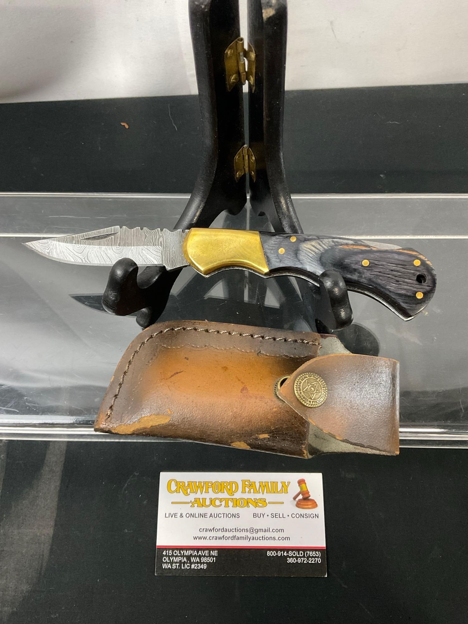 Handmade Damascus Steel Folding Knife w/ Brass & Black Tinted Wooden Handle & Custom Leather Sheath: Made from several layers of 1095 and 15N20 steel folded multiple times creating between 288 and 512 layers to form unique patterns in the blades. Each handle is custom fit as are the sheaths. Approx 3