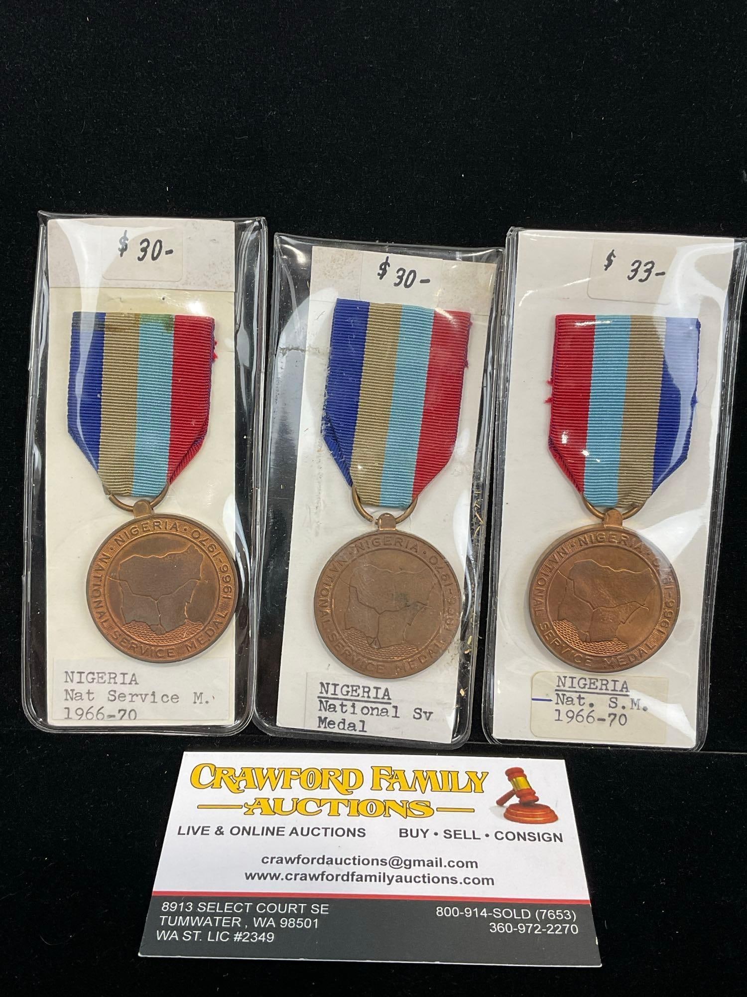 3x Nigeria National Service Medals, 1966-1970, bronze/copper, Blue/Grey/Lt.Blue/Red Ribbon: All from a single collection, these are briefly described on the tag and were kept in a display. They measure approx 6h x 3w x 2d inches. See pics. E-5300 