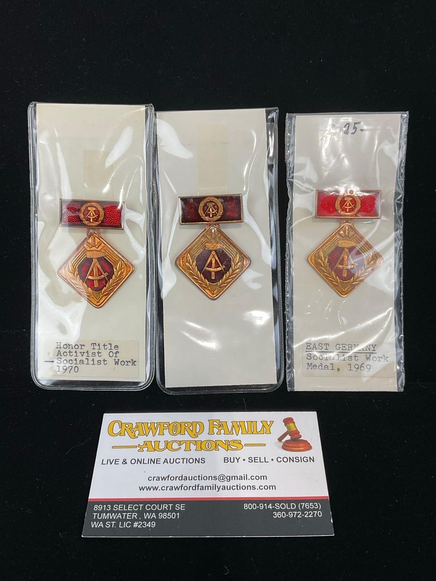 3 DDR East German Medals, Honor Title Activist of Socialist Work 1960s-1970, Enamel & Bronze: All from a single collection, these are briefly described on the tag and were kept in a display. They measure approx 6h x 3w x 2d inches. See pics. E-5300 
