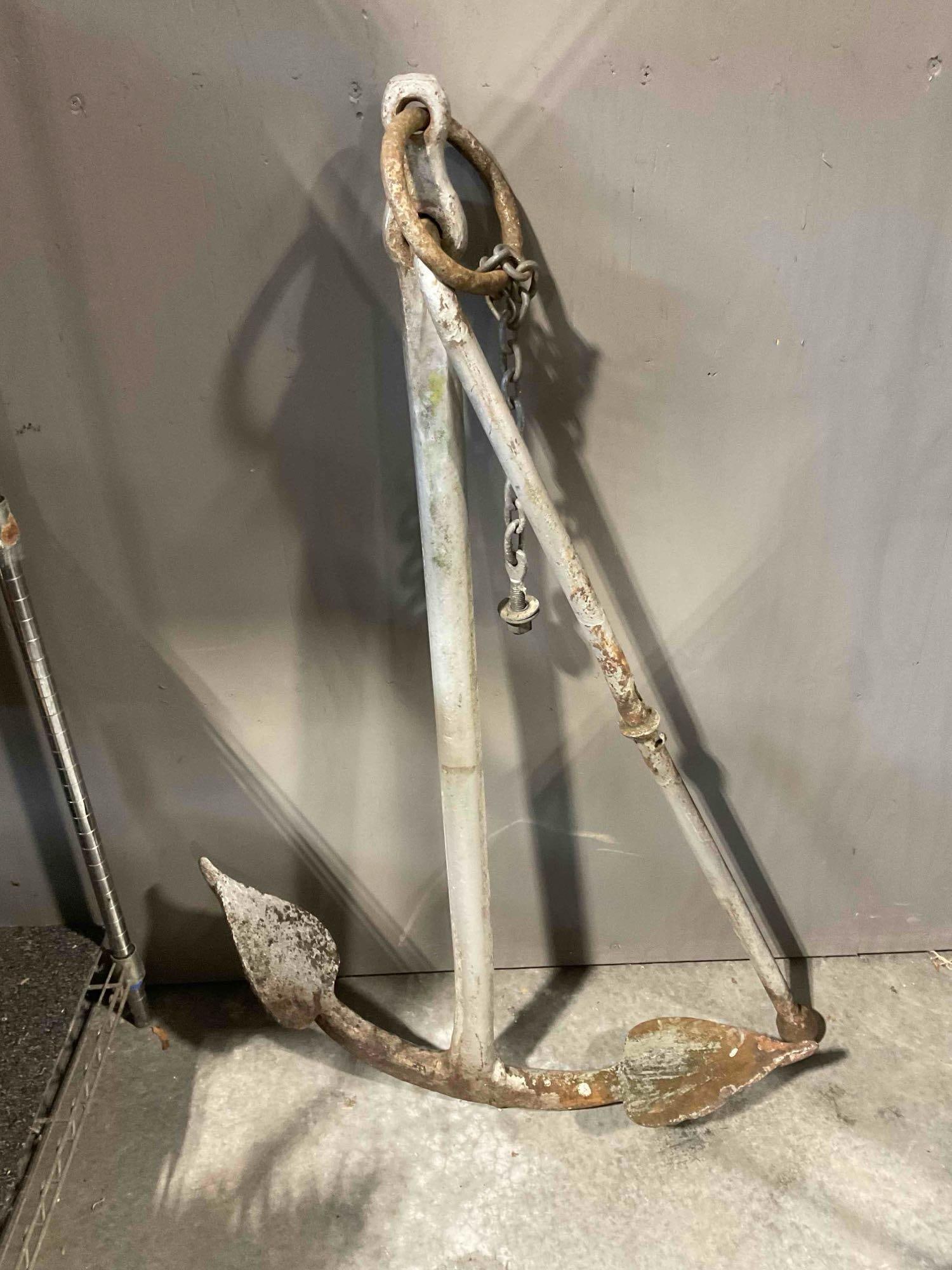 A Vintage 4Ft Metal Boat Anchor with Kick Stand Bar. Approximately 100 Lbs: *No in-house shipping, due to size and weight* Item is approximately 48" x 33" x 8". The anchor is in fair condition with rust and wear consistent with age. The is a significant bend in the forke