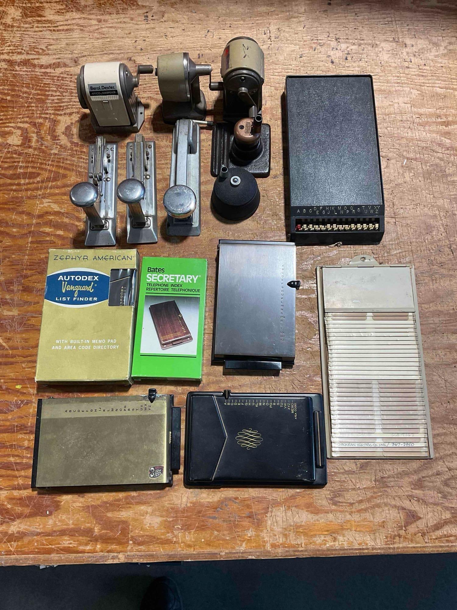 A Collection of Vintage Office Gear, Pencil Sharpeners, Staplers, and Phone Indexs: Fits into a container approximately 23" x 13" x 8". Items are in good condition with wear consistent with age. Some of the phone index's are new in box. V-5360 