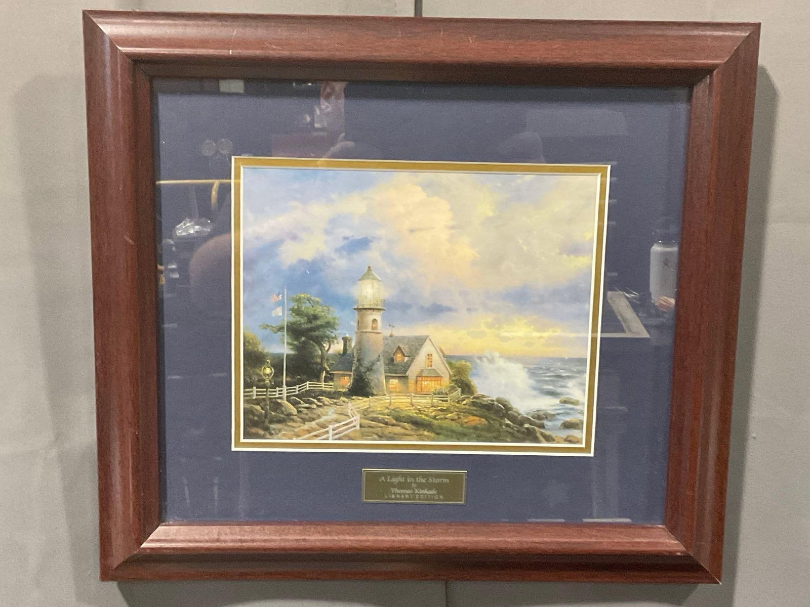Framed Library Edition Lithograph, titled A Light in the Storm by Thomas Kinkade, 17h x 19w inches: Appears to be in good shape. The outside dimensions measure approx 17h x 19w x 2d inches. See pics. E-414