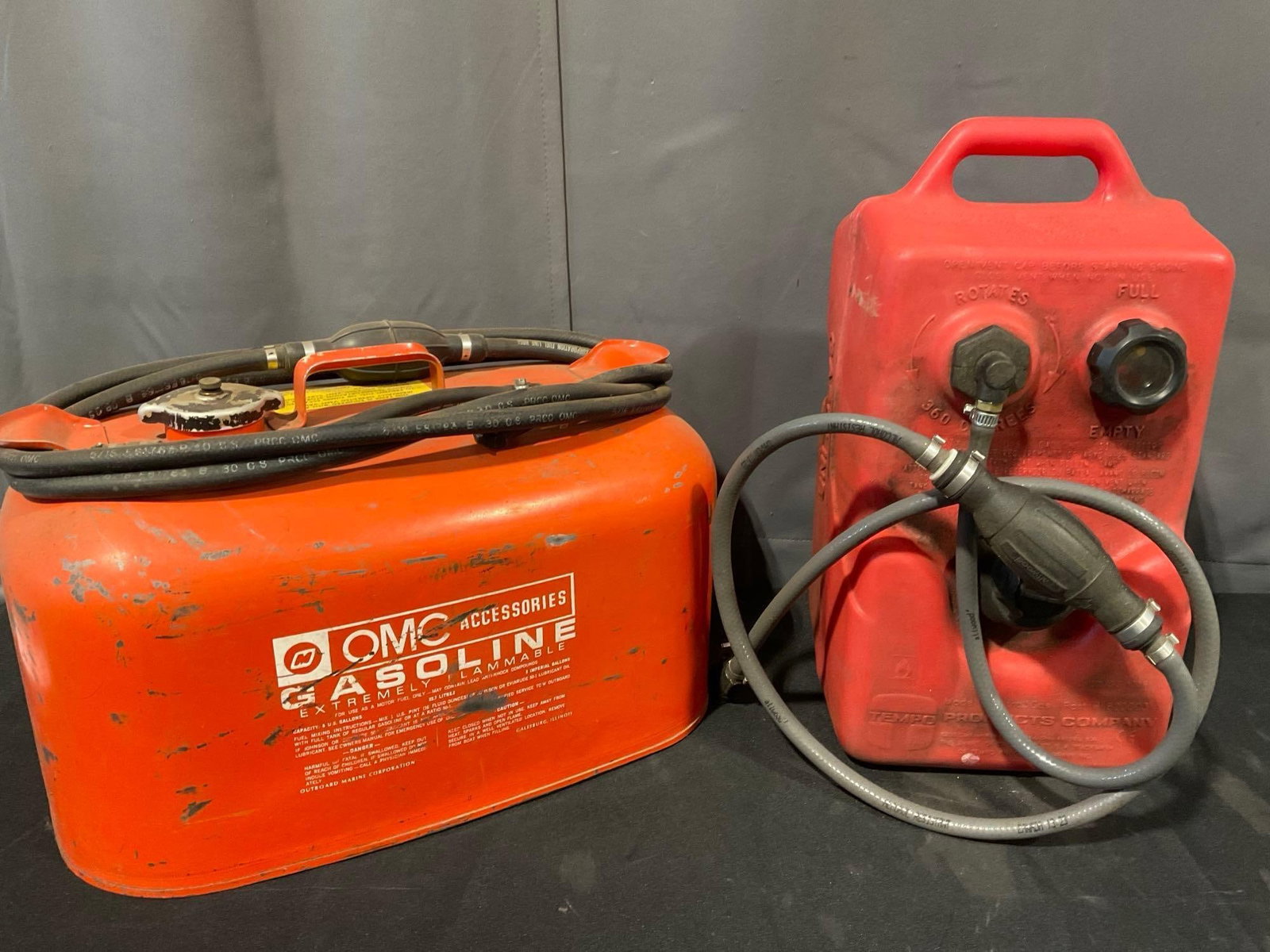 OMC Accessories & Tempo Products Company Gas Cans, both have some gas: *No in-house shipping available, hazardous materials* Appears to be in fair to good shape. The piece measures approx 23h x 17w x 11d inches. See pics. E-5600 *No in-house shipping available,