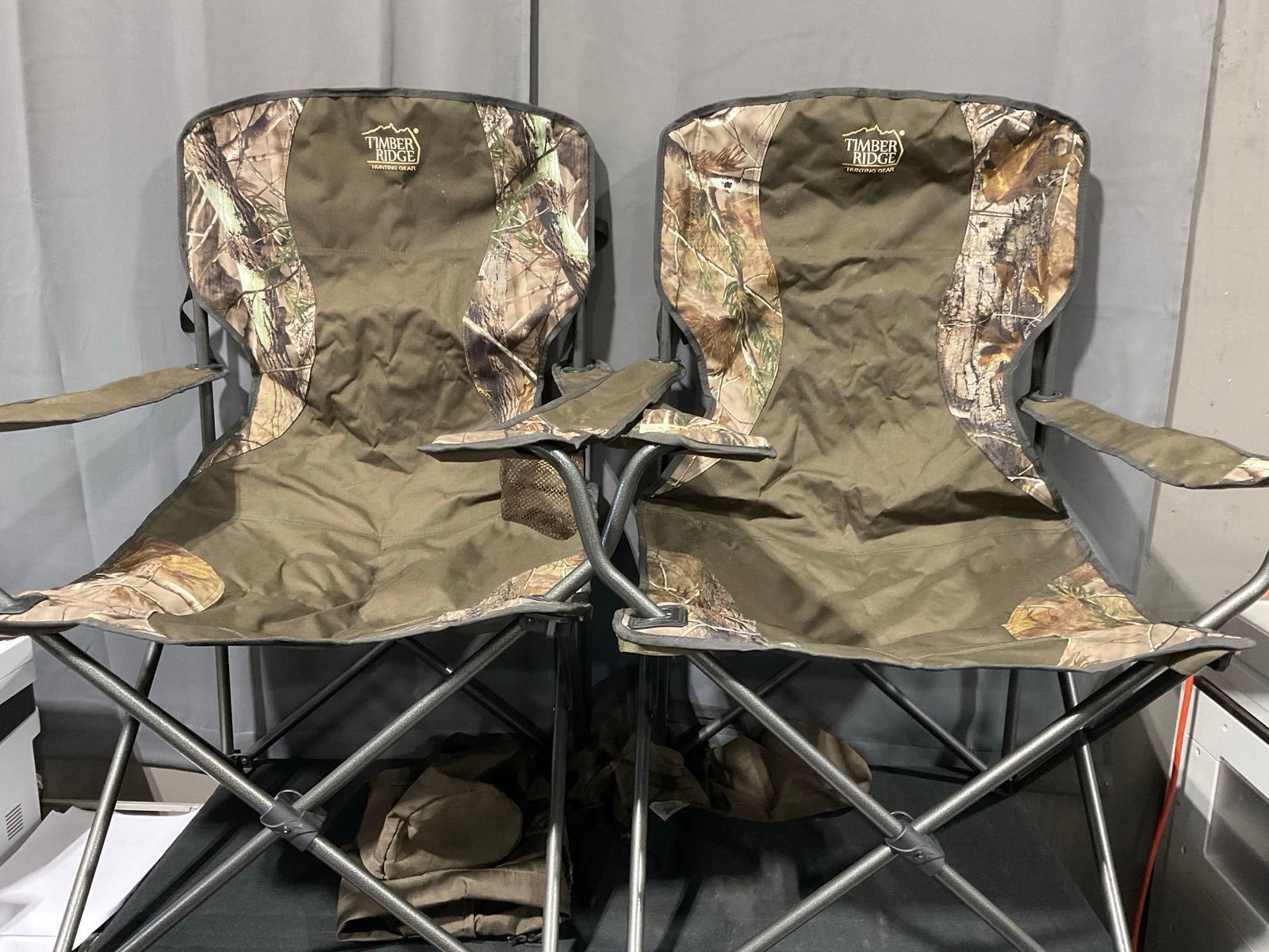 Pair of Timber Ridge Folding Chairs, Camo & olive drab cloth, w/nylon cases: Appears to be in good shape. The piece measures approx 40h x 18w x 19d inches. See pics. E-5600 *Freight Required if shipped, Buyer Arranged/Responsibility*