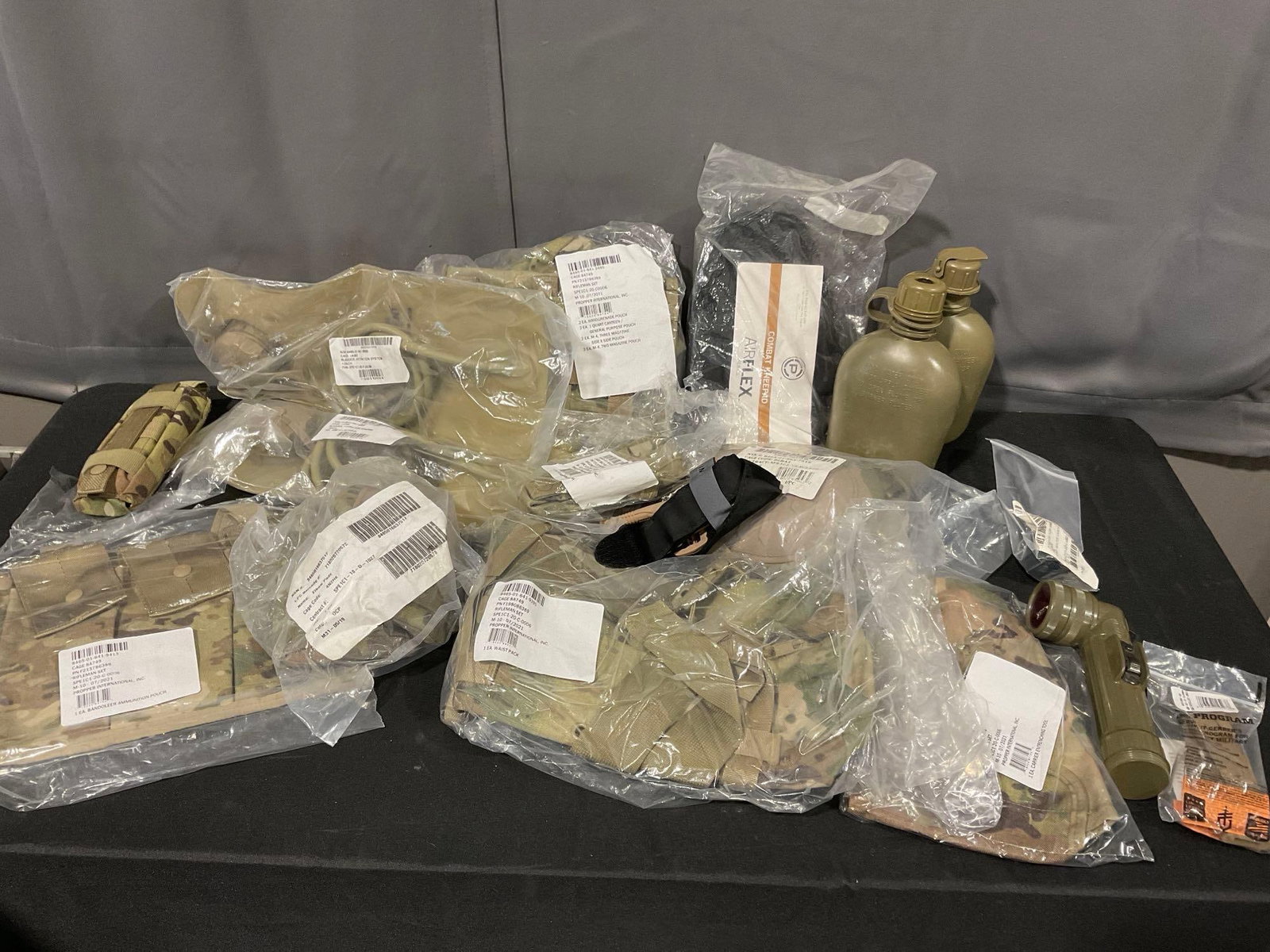 Asst Combat Supplies, Kneepads, Flashlight, 2 Canteens, 2 Magazine Holsters, 2 Hydration Bladders...: mostly in the original packaging, unopened. Appears to be in good shape. The pieces fit in a tub measures approx 13h x 23w x 15d inches. See pics. E-5880