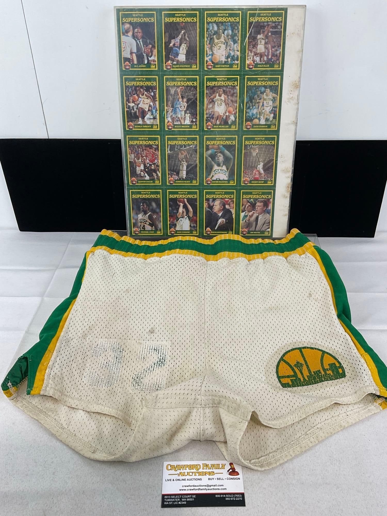 Sheet of Seattle Supersonics Basketball Cards, & Rawlings Supersonics Shorts, #32, some wear: Appears to be in fair to good shape, the cards look to be in good shape. The Shorts are worn, and the Acrylic display frame is scratched. The piece measures approx 3h x 15w x 12d inches. See pics.