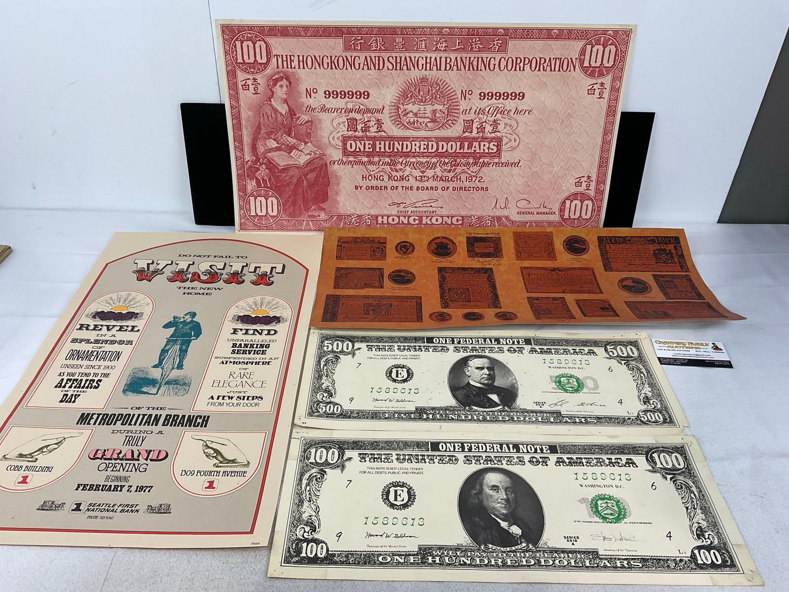 Posters & Blown Up Vintage Money Prints, 100 & 500, & Hong Kong 100 dollars notes, 14 x 24 inches: Also includes Seattle First National Bank Opening Poster, & Poster of antique 1776 bills, Eight shilling New York Water bill, 1 Spanish milled dollar & more Appears to be in good shape. 