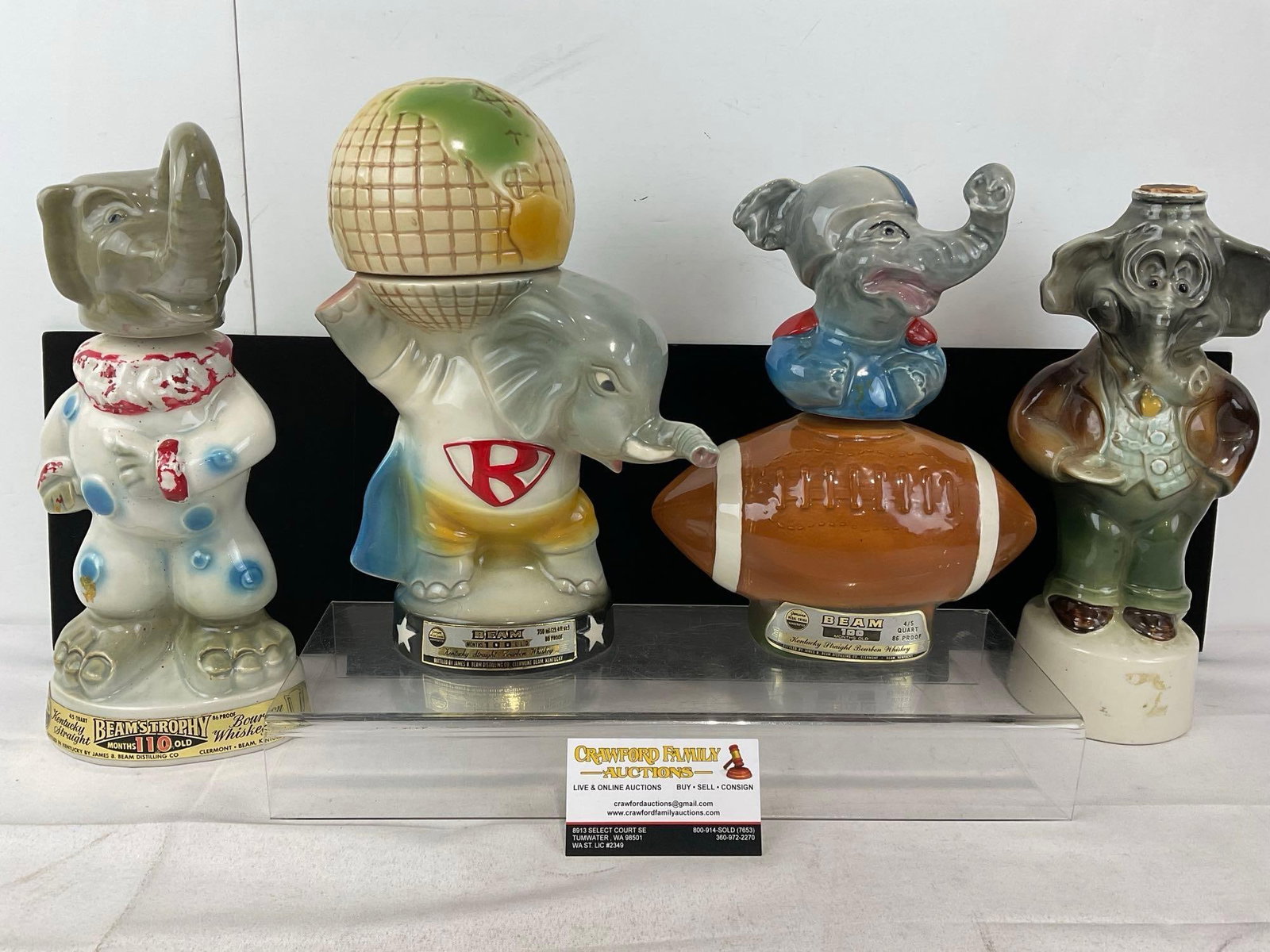 4 Figural Elephant Shaped Jim Beam Whiskey Bottles, Clown, Superman, Football & Business Man: Appears to be in fair to good shape, the superhero style one heavily cracked along the back side, possibly some wear near the spout as well. The piece measures approx 14h x 13w x 13d inches. See