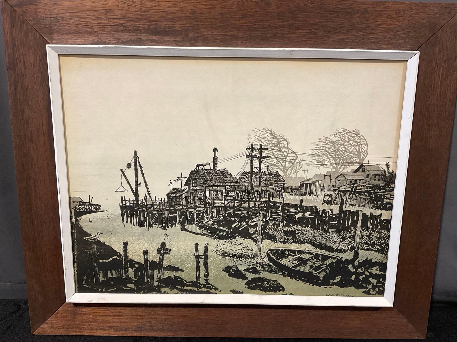 Framed Serigraph Dilapidated Fishing Town Scene, by Mark Wheeler, 26x32 inches: Appears to be in good shape. The piece measures approx 26h x 32w x 3d inches. See pics. E-6610