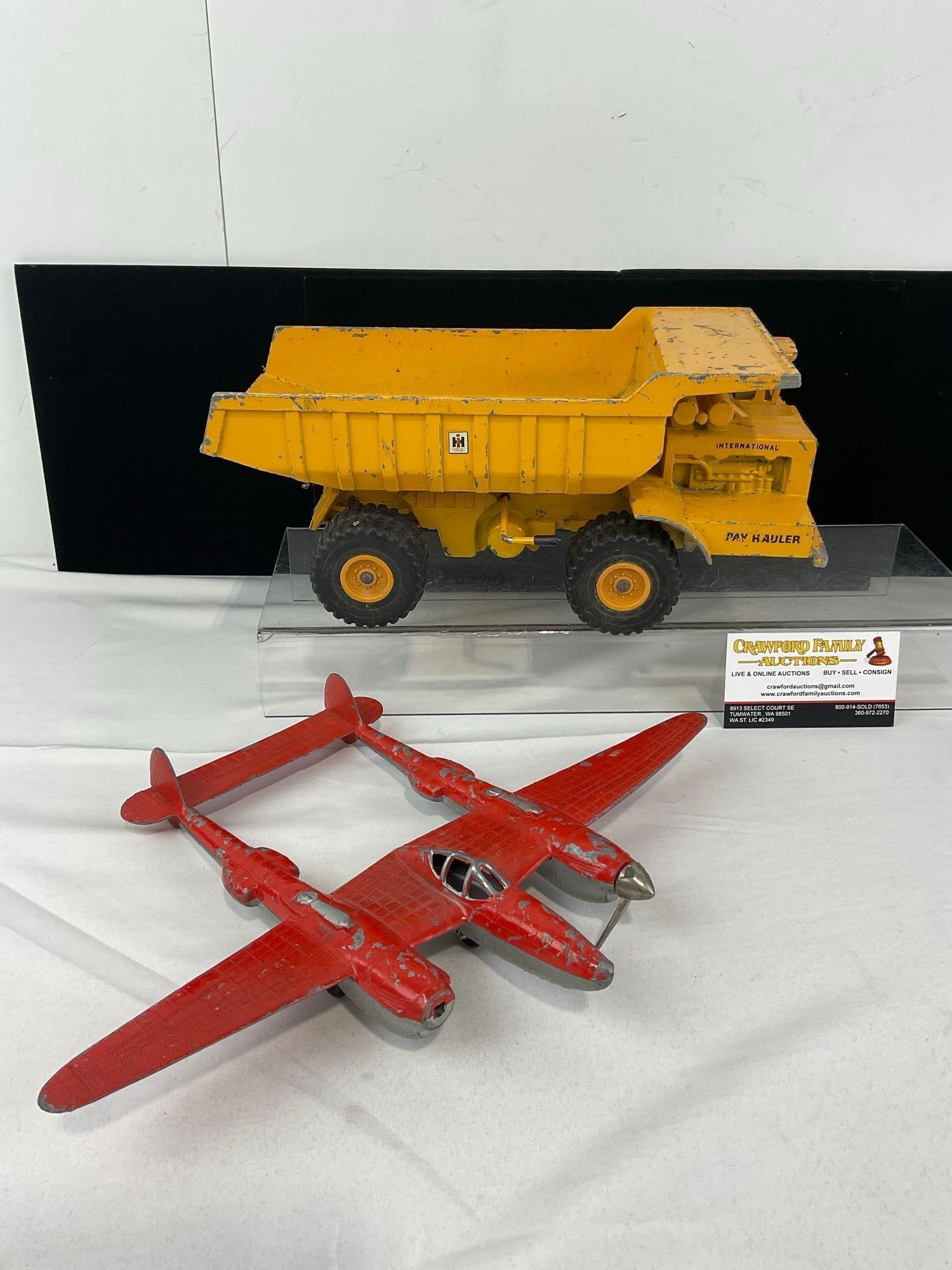 2 Vintage Metal Toys, Hubley P-38 Lightning & Ertl International Harvester Dump Truck Pay Hauler: Appears to be in fair shape, shows lost finish on both pieces, missing propellers on the plane. The piece measures approx 7h x 14w x 10d inches. See pics. E-6610