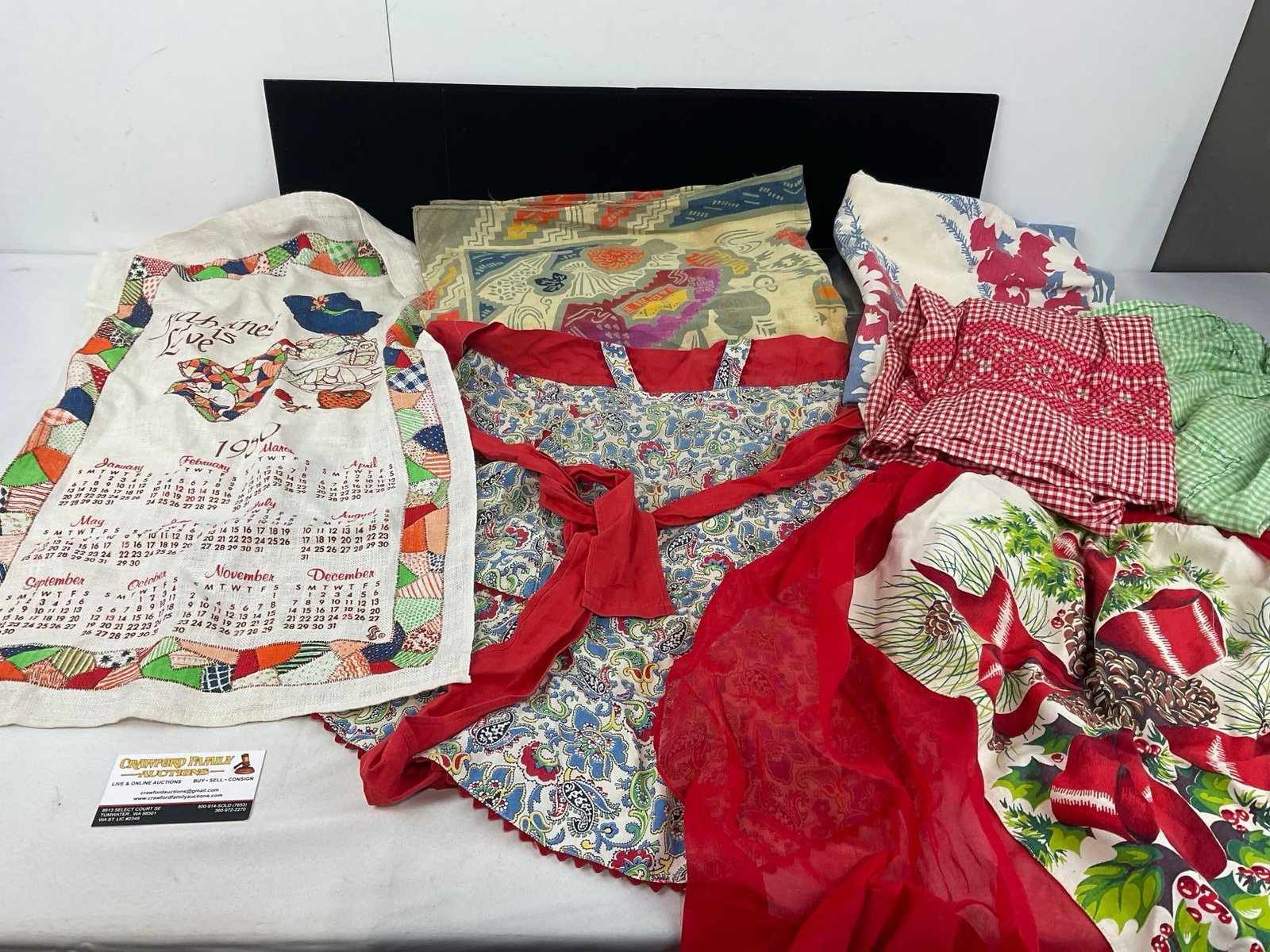 Variety of 4 Handmade Aprons, Cloth Calendar, & 2 Tablecloths, Floral patterns, approx 36x36 inches: See pics for condition. The piece measures approx 18h x 5w x 5d inches when rolled up. E-6610
