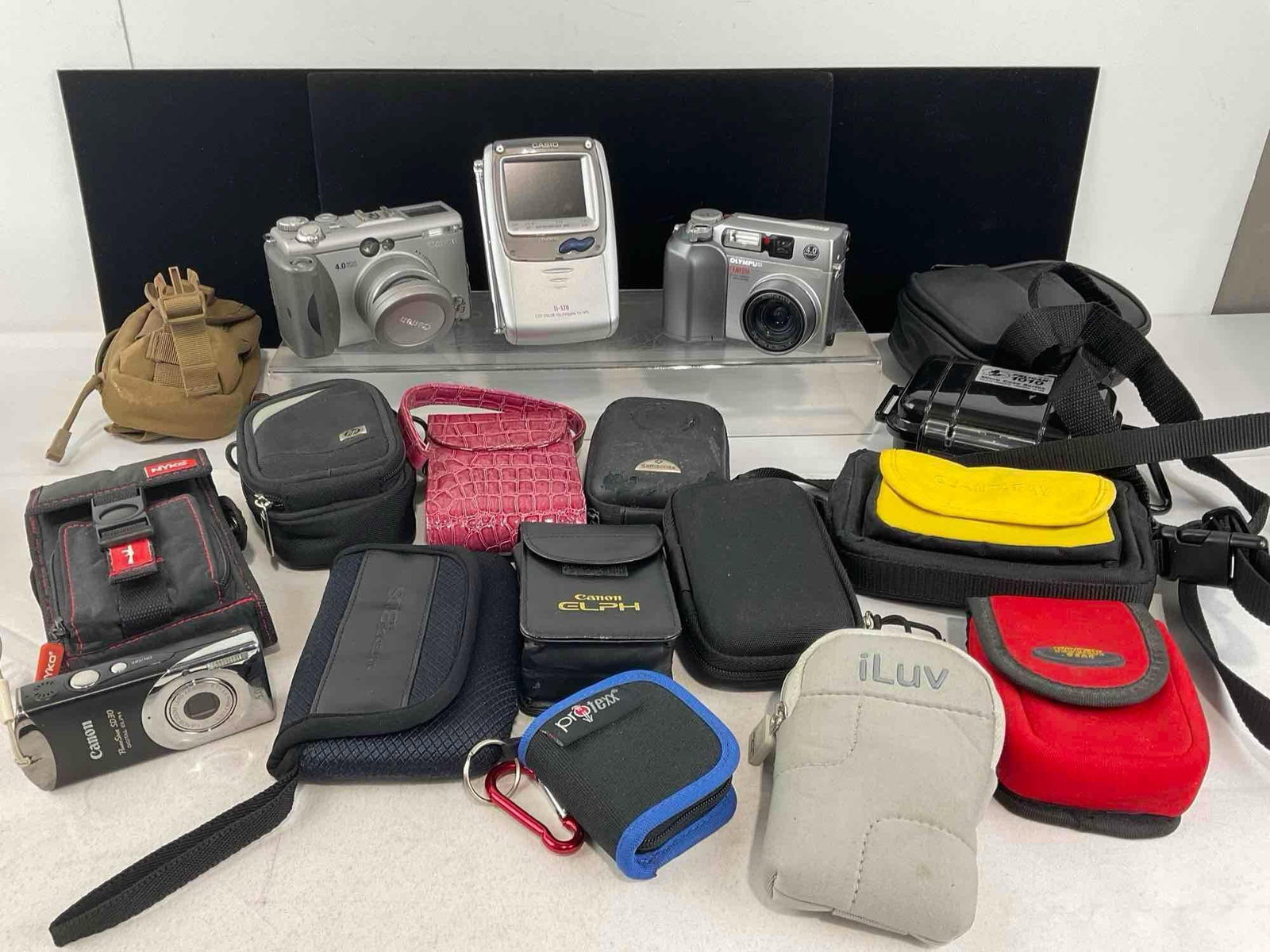 Variety of Cameras, Casio Portable TV-970B, Canon PowerShot Olympus C-4000, w/extra cases: See pics for condition. Measures approx 8h x 9w x 12d inches. E-4320