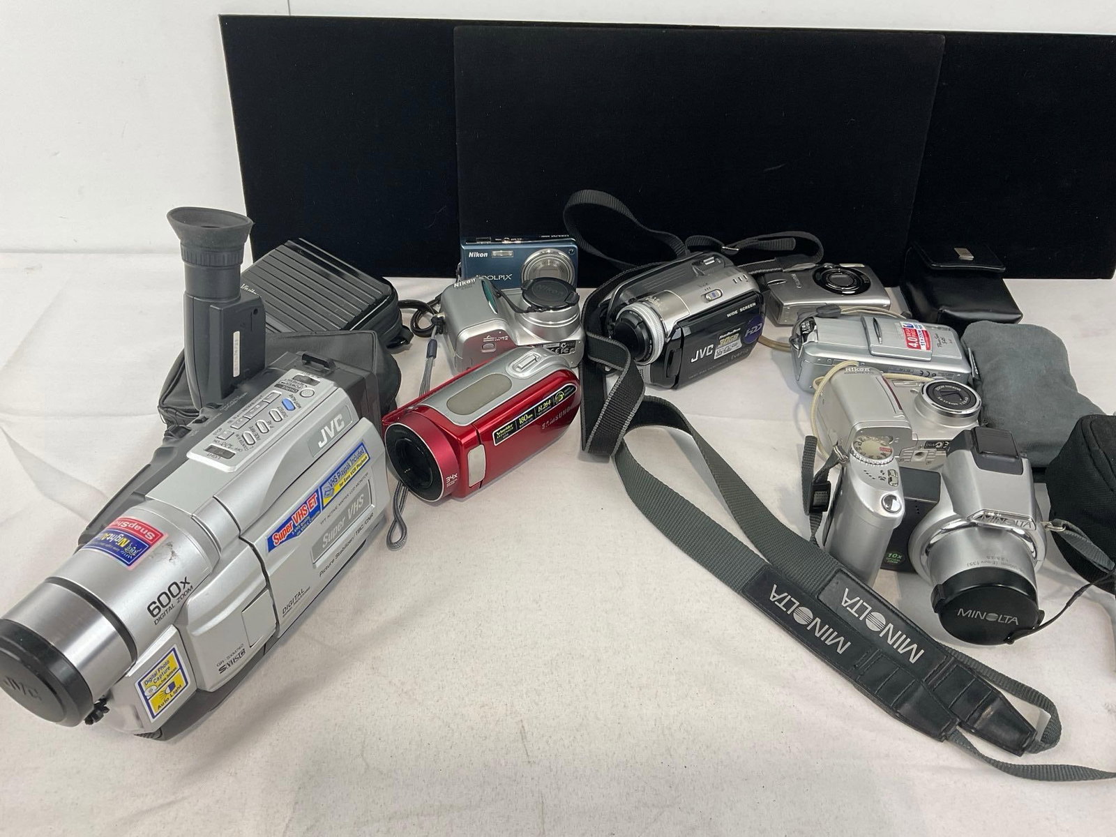 Variety of Cameras, Camcorders, JVC, Minolta, Nikon Coolpix & more: See pics for condition. Measures approx 8h x 13w x 10d inches. E-4320