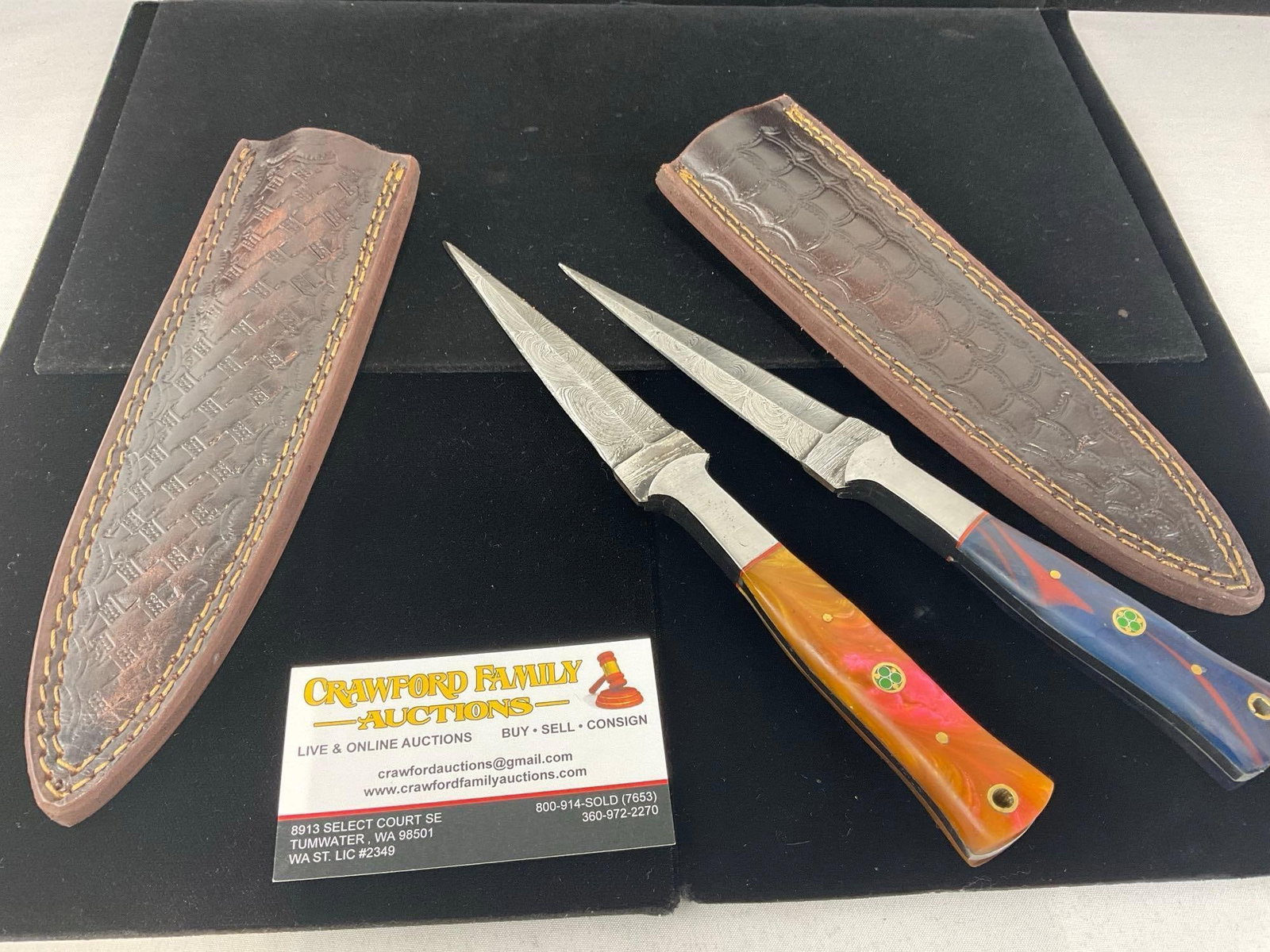 Pair of Damascus Steel style Daggers w/ Orange & Red/Black Resin Handles & Leather Sheaths: All these knives are from the same collection. See pics for condition. Blade measures approx 5 inches. Measures approx 11h x 3w x 3d inches. E-3440