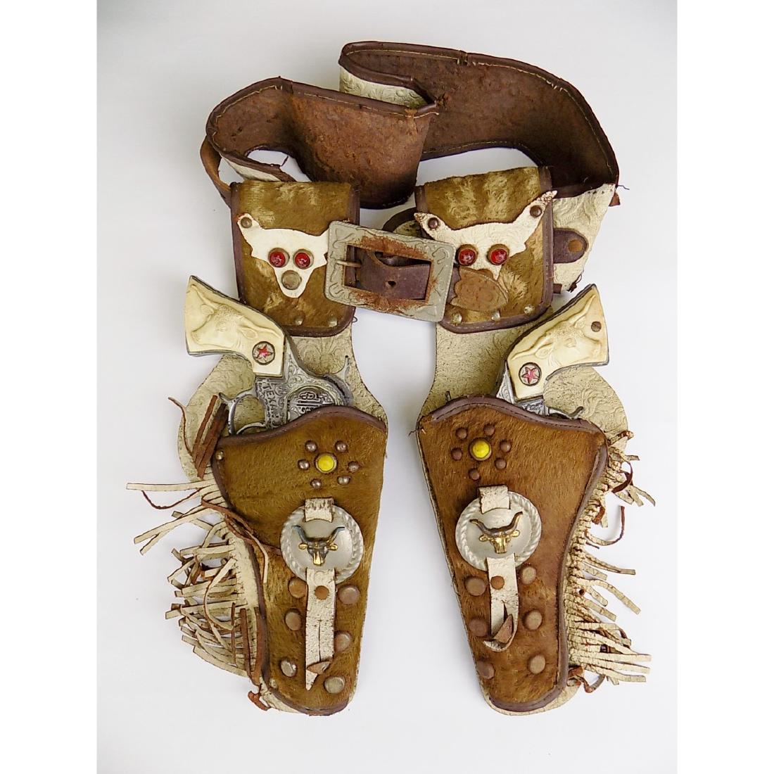 CIRCA 1950S DOUBLE HOLSTER WITH 2 TEXAN JR. CAP GUNS: COWHIDE STYLE LEATHER LOOK WITH STUDS, JEWELS ETC. GUNS WORK.