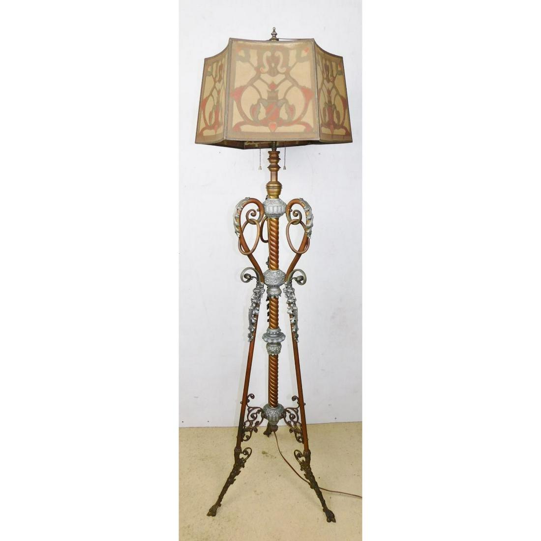 ANTIQUE VICTORIAN PIANO LAMP: A DECORATED ANTIQUE PIANO LAMP. FEATURES THREE CLAW FEET IN BRASS, FACE DECORATIONS ON TOP OF LEGS, AND DECORATED SHADE. MEASURES 60" TOTAL HEIGHT