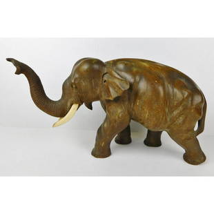 CARVED WOODEN ELEPHANT: A CARVED BALSA WOOD ELEPHANT FIGURE WITH BONE TUSCS. UNSIGNED. ONE TUSK HAS SOME "BATTLE" DAMAGE. PLEASE SEE PHOTOGRAPHS. MEASURES 8"H X 16"W.