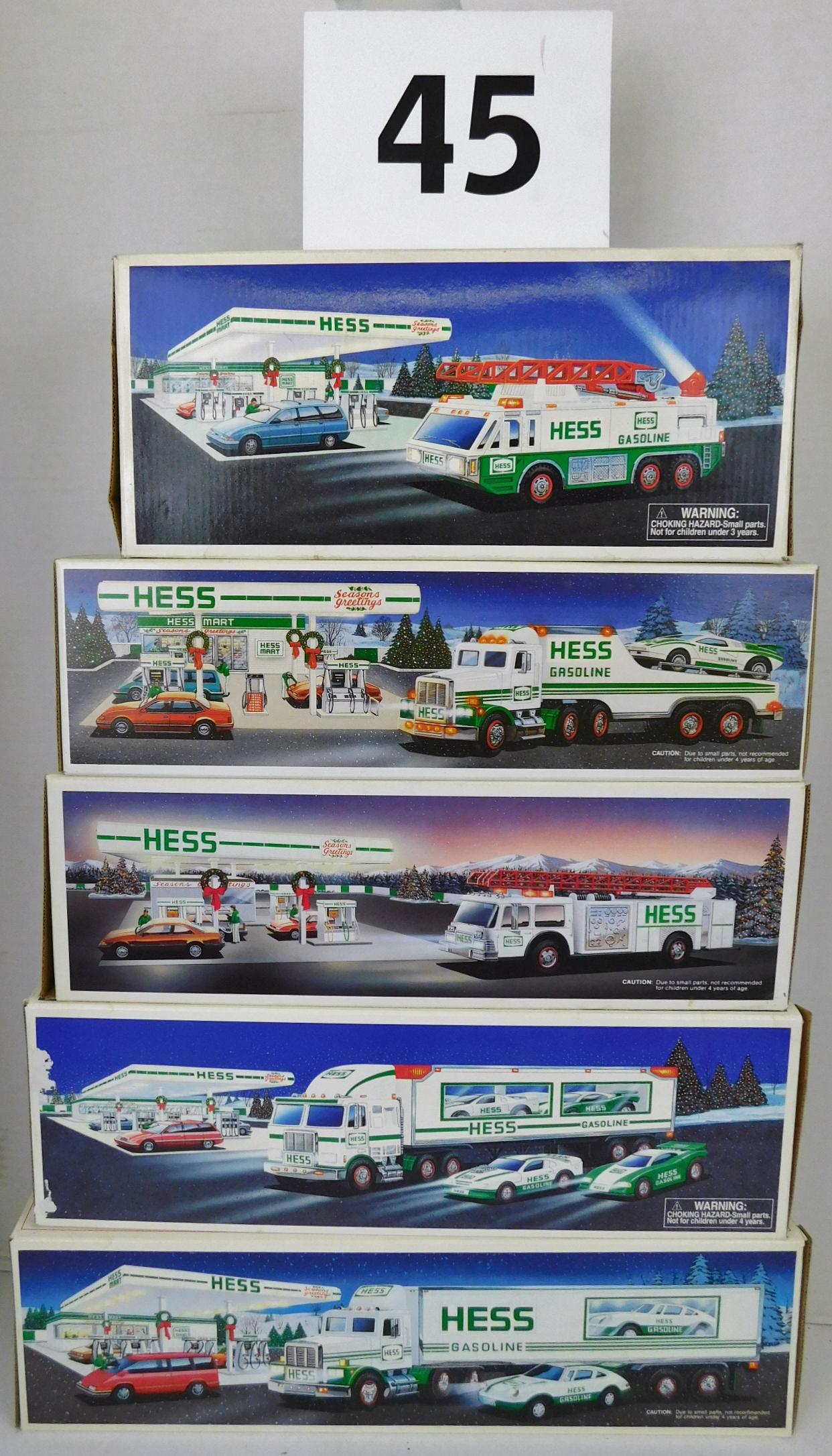 LOT OF FIVE HESS TRUCKS IN BOXES: A LOT OF FIVE BATTERY OPERATED HESS TRUCKS IN THE ORIGINAL BOXES. 1996 SEARCH AND RESCUE TRUCK, 1989 LADDER TRUCK, 1991 RACE CAR TRANSPORT, ONE 1992 AND 1997 CAR TRANSPORTS.