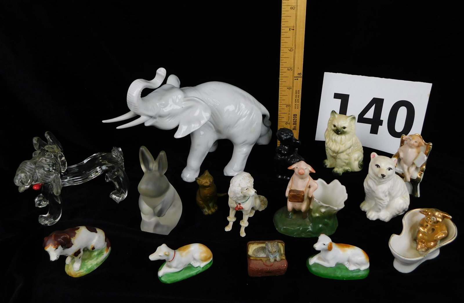 GLASS AND PORCELAIN ANIMAL FIGURNES: A LOT OF GLASS AND PORCELAIN ANIMAL FIGURINES. A WHITE ROYAL DUX ELEPHANT MEASURING 9.5"L X 4"W X 6"H. GOEBEL BLACK POODLE FIGURINE, GERMAN MARKED PIGS, AND MULTIPLE UNMARKED DOGS AND MORE.