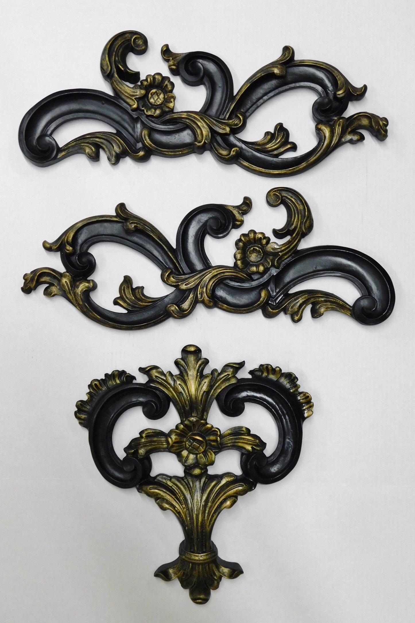 THREE DECORATIVE CARVINGS: A LOT OF THREE BLACK DISTRESSED DECORATIVE CARVINGS. TWO MEASURE 22.5"W X 8.5"H AND ONE MEASURES 15.5"H X 14.5"W.