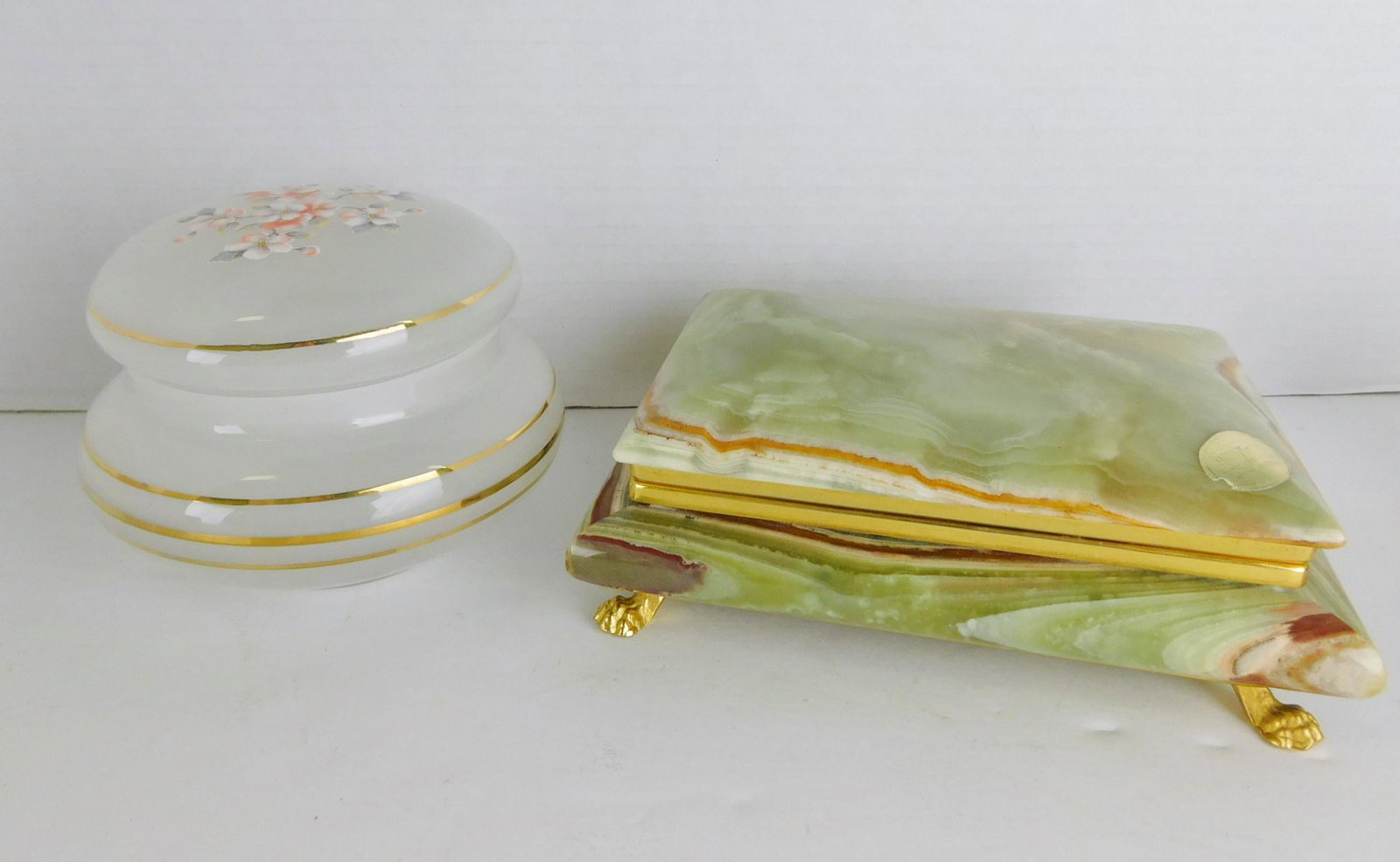 PAIR OF DECORATED DRESSER BOXES: A PAIR OF DECORATED DRESSER BOXES. ONE WHITE OPALESCENT GLASS WITH FLORAL MOTIF AND GOLD GILT PAINT. MEASURES 5.5" DIAMETER X 3.5"H. ONE ITALIAN CLAW FOOT ONYX DRESSER BOX WITH RED FELTED INTERIOR. ME