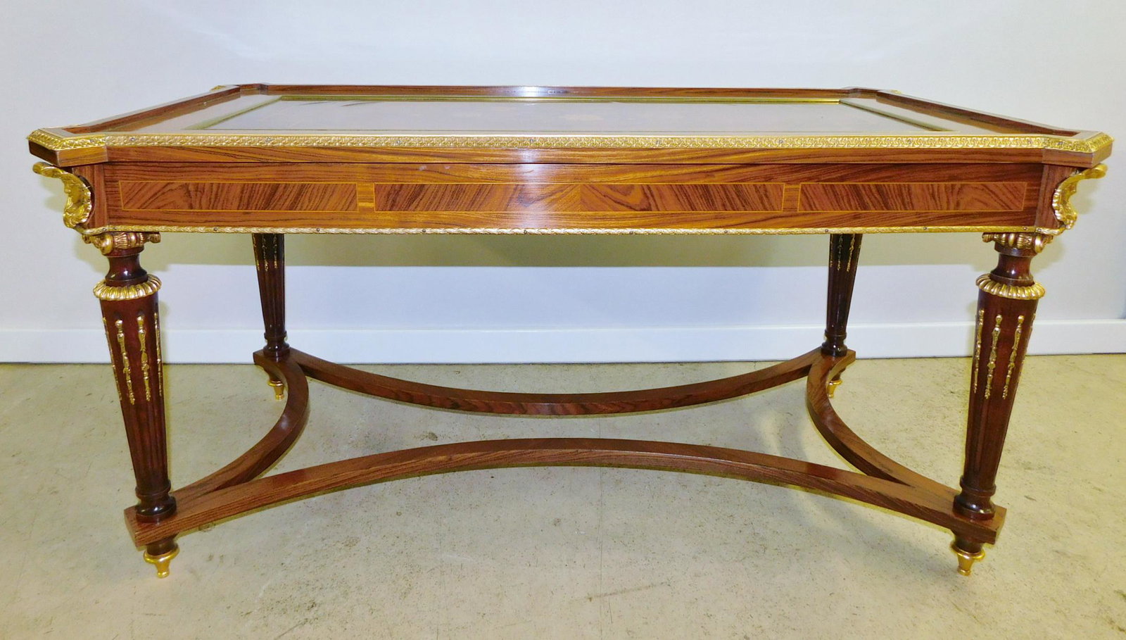 FIGURAL MARQUETRY COFFEE TABLE: A MARQUETRY STYLE INLAID COFFEE TABLE WITH BRASS FIGURAL CORNERS, EDGES, FEET, AND DECORATION. FLORAL INLAY IN THE CENTER. PLEASE SEE PHOTOGRAPHS. MEASURES 43"W X 24"D X 21"H.
