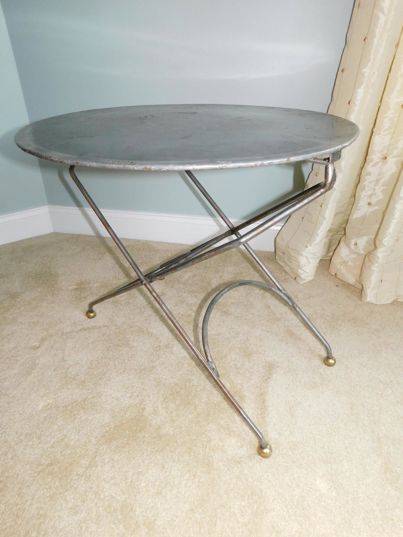 ROUND METAL TABLE: A ROUNT METAL TABLE WITH PAINTED BRASS FEET. MEASURES 24"DIAMETER X 23"H.