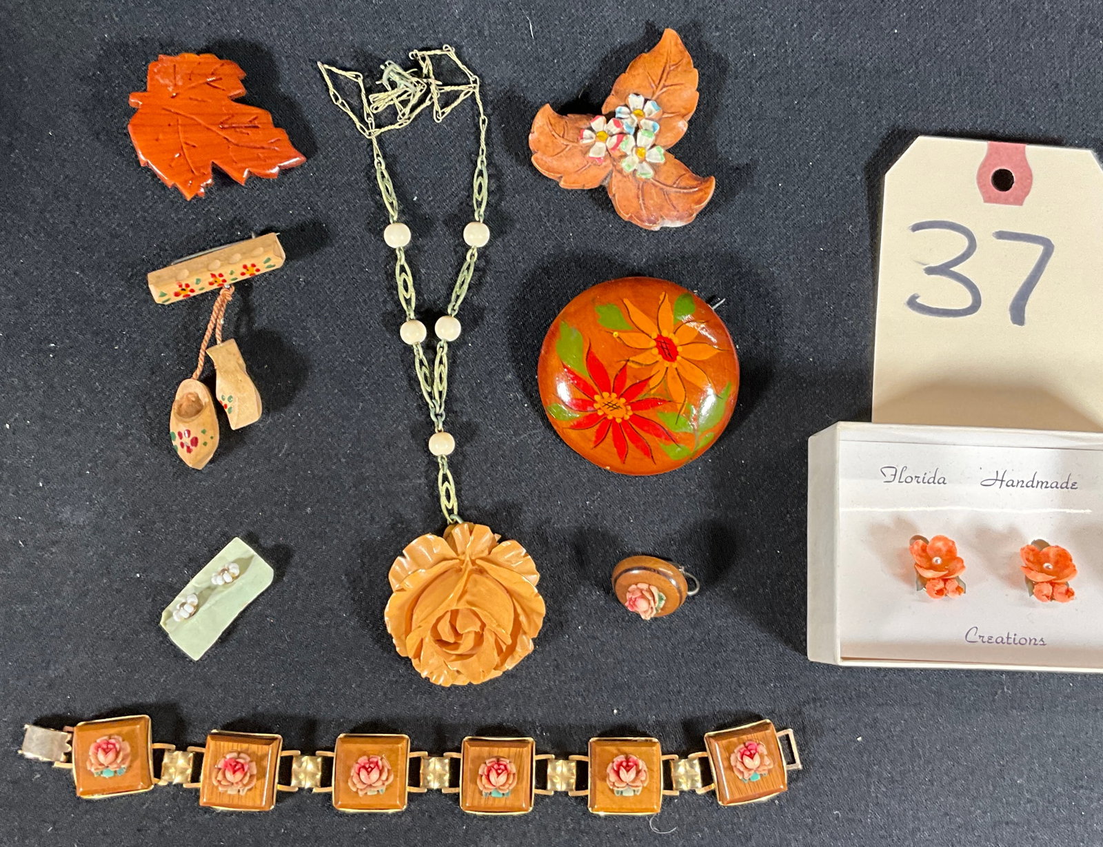 CARVED AND HAND PAINTED WOODEN JEWELRY LOT.: CARVED AND HAND PAINTED WOODEN JEWELRY LOT. INCLUDES PINS, BRACELETS, EARRINGS, AND MORE. Condition All property is sold in "as is" condition and all sales are final. Teel Auctions and its consignor m