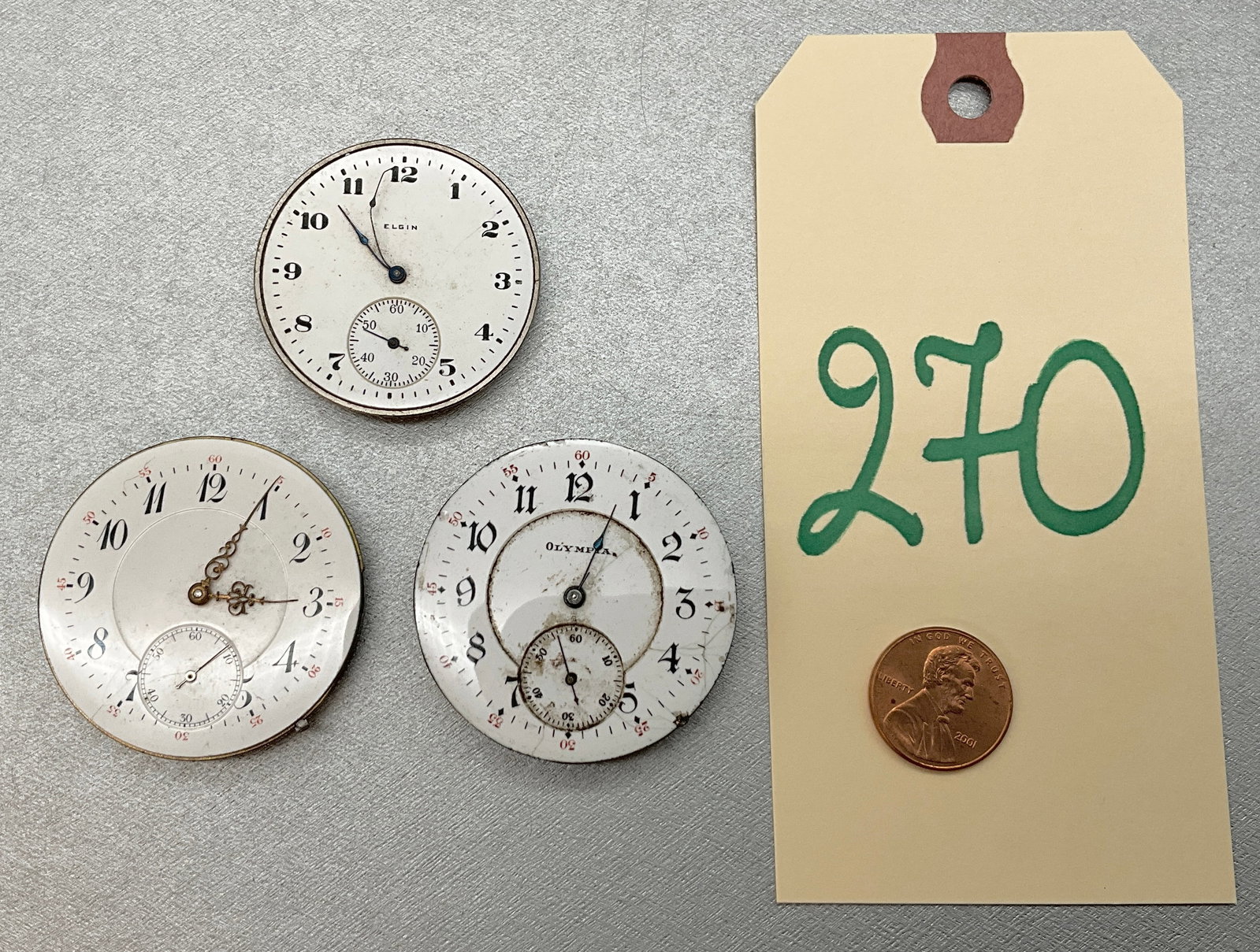 3 PC VINTTAGE WATCH FACES/MECHANISMS FROM OLYMPIA, ELGIN, AND IWC PROBUS.: 3 PC VINTTAGE WATCH FACES/MECHANISMS FROM OLYMPIA, ELGIN, AND IWC PROBUS. Condition All property is sold in "as is" condition and all sales are final. Teel Auctions and its consignor make no represent