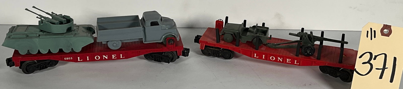 2 PC LIONEL 6803 FLAR CARS WITH MILITARY VEHICLES.: 2 PC LIONEL 6803 FLAR CARS WITH MILITARY VEHICLES. Condition All property is sold in "as is" condition and all sales are final. Teel Auctions and its consignor make no representations or warranties, e
