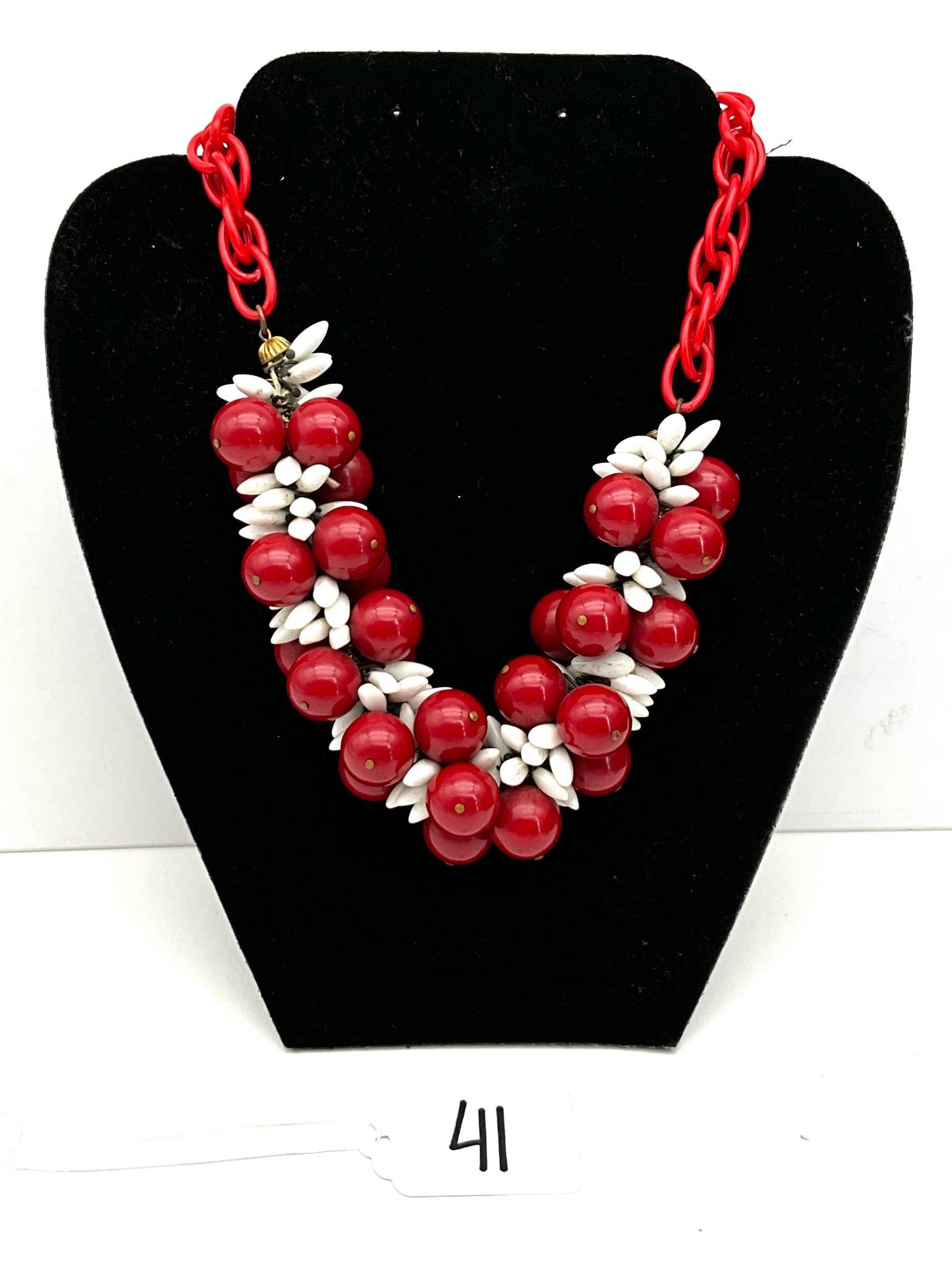 Red and White Acrylic Resin Necklace with 14-Inch Length: Acrylic resin necklace composed of red spheres paired with white floral-like accents. The necklace measures 14 inches in length and features a red chain with a claspl closure. The bold design showcase