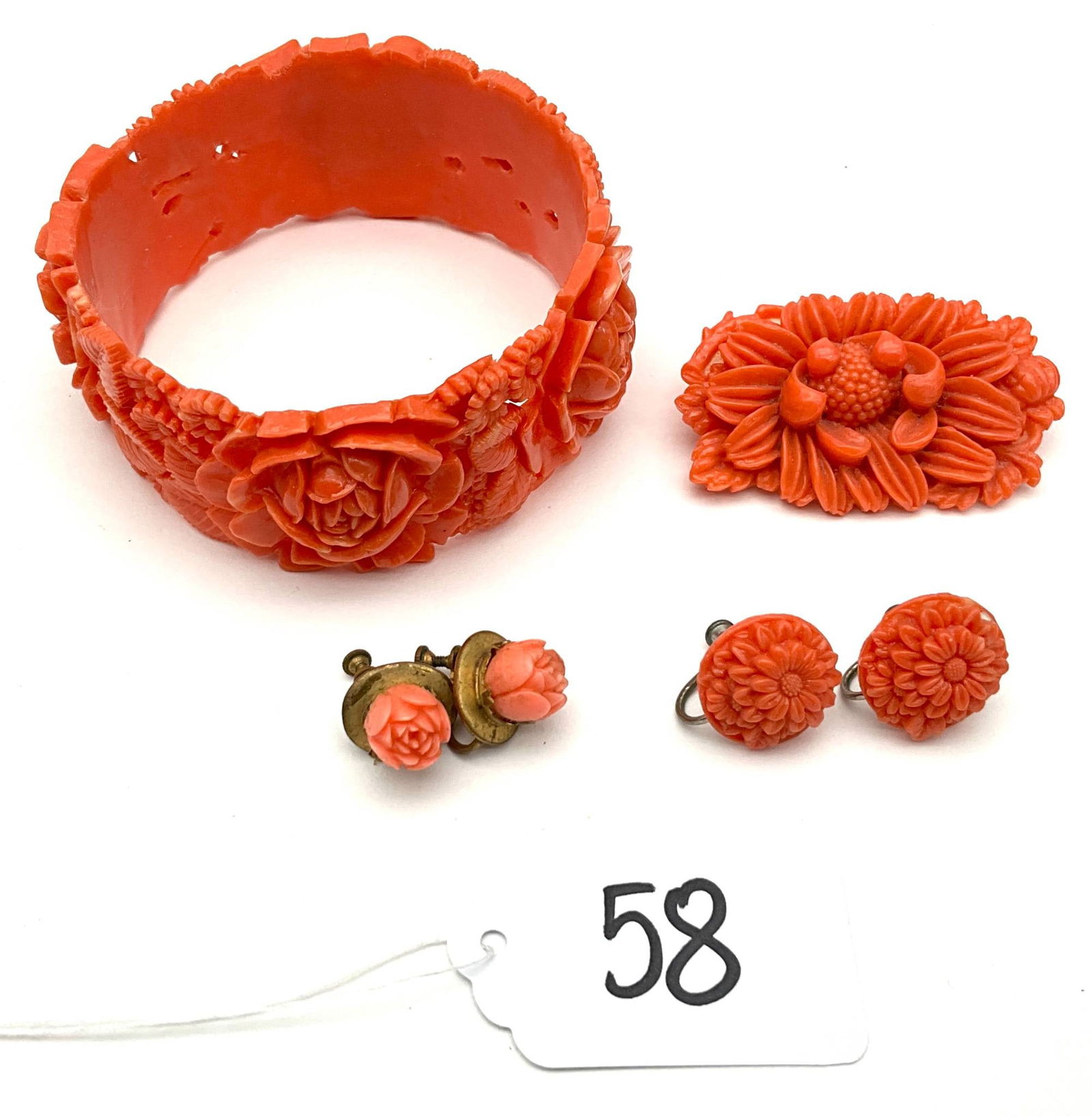 Carved Bakelite Jewelry Set with Bracelet, Brooch, and Earrings: Carved Bakelite jewelry featuring floral motifs, including a bracelet (1.25" width x 2.5" diameter), a brooch marked "Made in Japan" (2" x 1.25"), and two pairs of screw-back earrings. The bracelet an