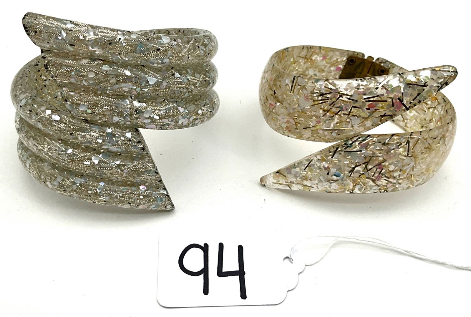 Confetti Lucite Bracelets With Spiral and Pointed Design: Unique confetti Lucite bracelets, each featuring a distinctive design. One bracelet has a layered spiral profile, while the other showcases a sharp, pointed design. Both have a width of 2 inches and a