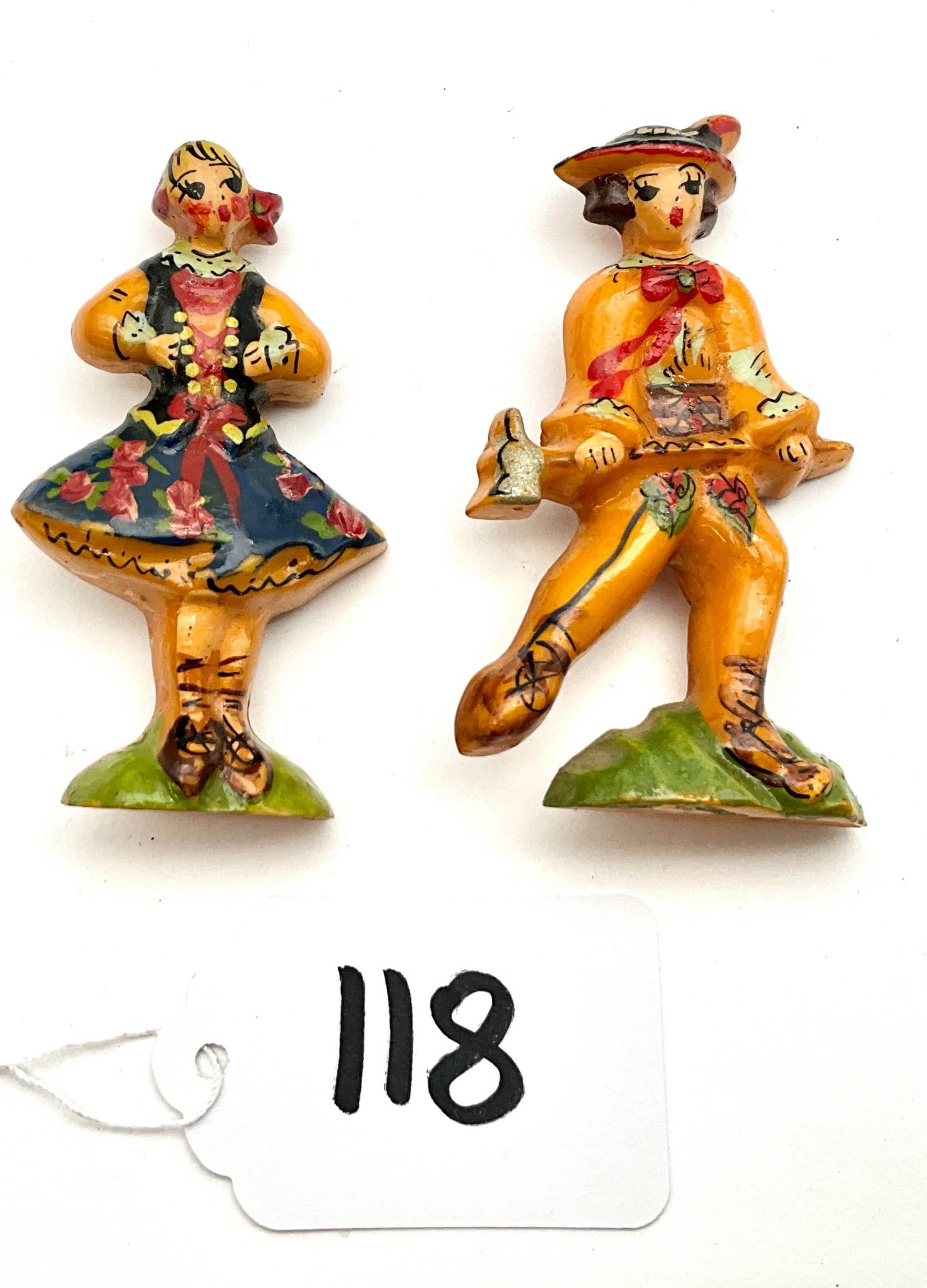 Vintage Bakelite Pins in Folk Costume Design: Vintage Bakelite pins featuring a man and woman in folk costume design. These decorative pins measure approximately 2.5 inches each. Detailed hand-painted designs and functional pin closures are visib