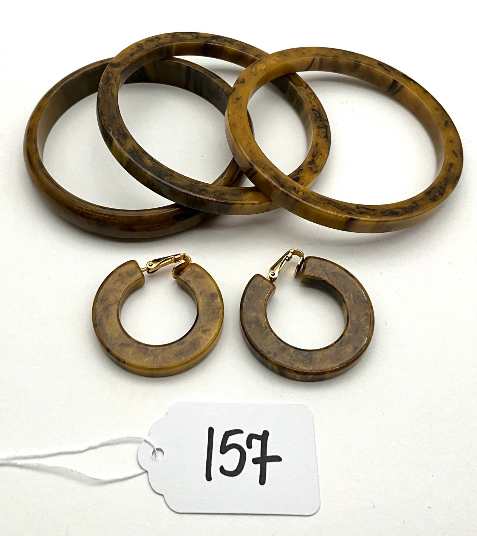 Vintage Bakelite Bangle and Hoop Earring Set: Vintage Bakelite jewelry including four marbled bangles and a pair of matching hoop earrings. The bangles vary slightly in color and pattern, showcasing the characteristic marbled finish of Bakelite.